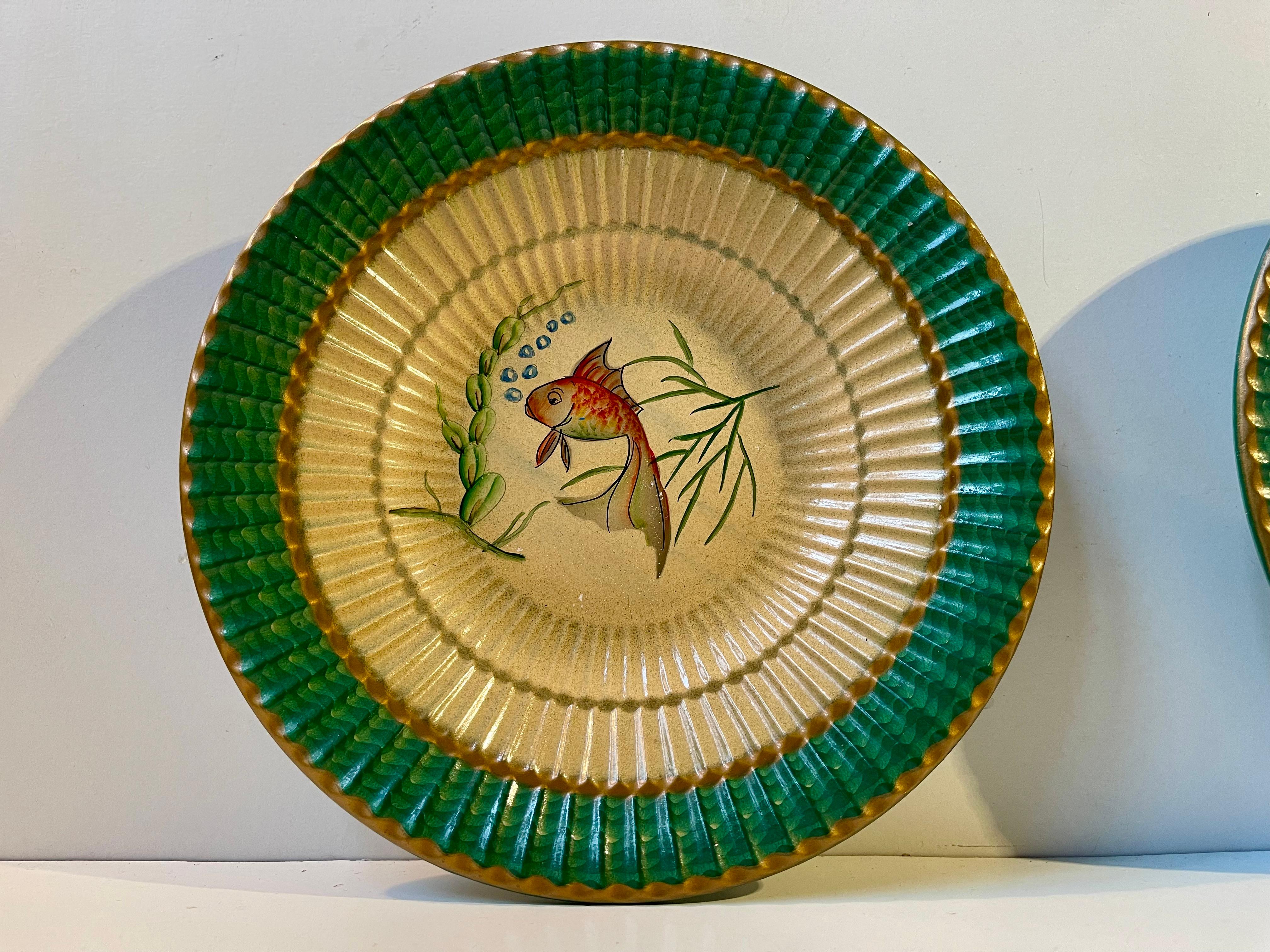 Un bonito y elegante par de platos o cuencos de mayólica italiana para dulces, galletas, fruta, etc. Cada una pintada a mano con distintos motivos de peces de colores sobre un dessin estriado de estilo art déco. 
Medidas: P: 19,5 cm, A: 4 cm. 

El