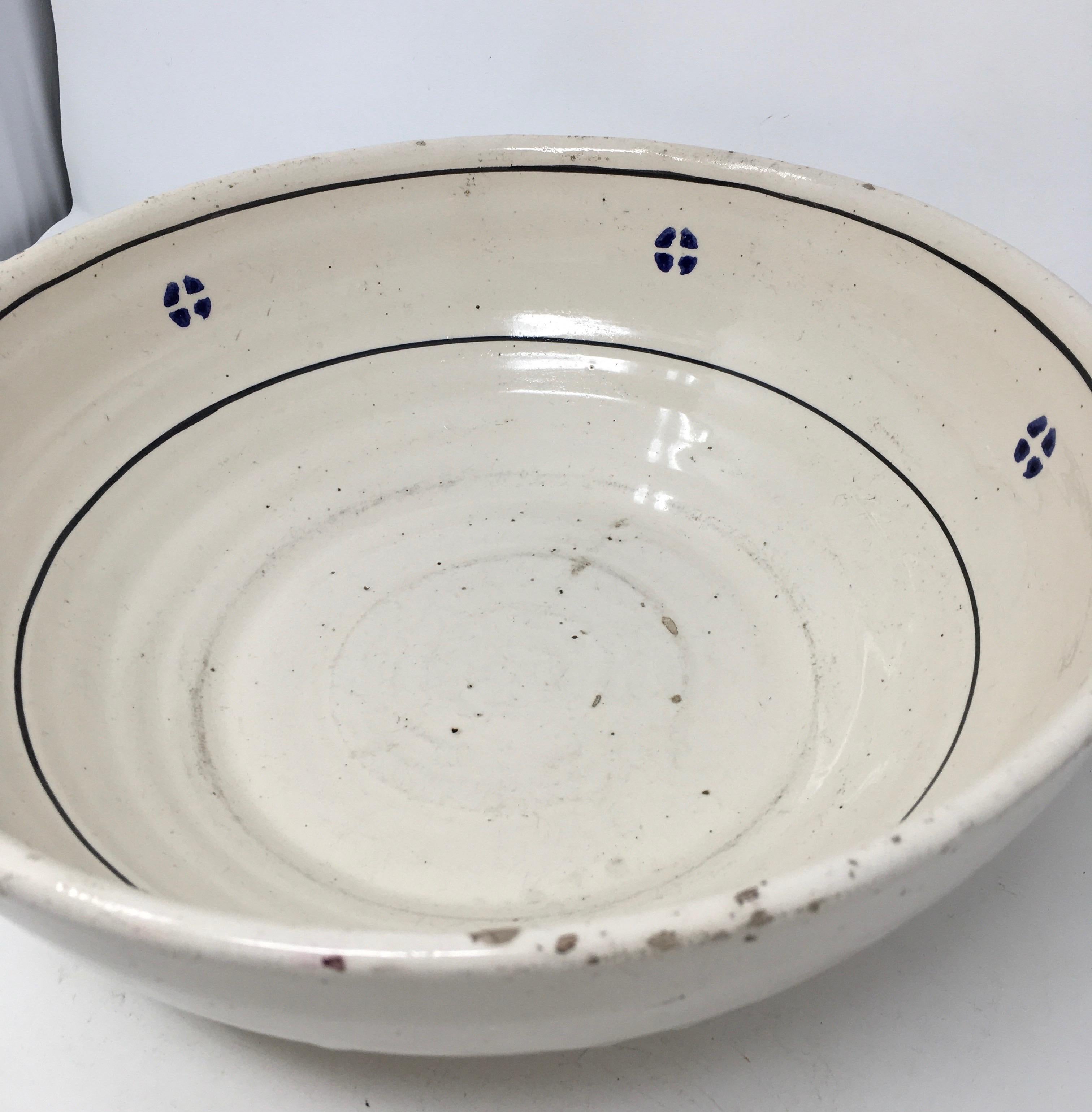 This hand painted Italian antique terracotta bowl is from the region of Puglia, Italy. The simple blue floral design around the rim is characteristic of this area. The shape is nice too. It is a bowl, but a very shallow one. This bowl shows wear