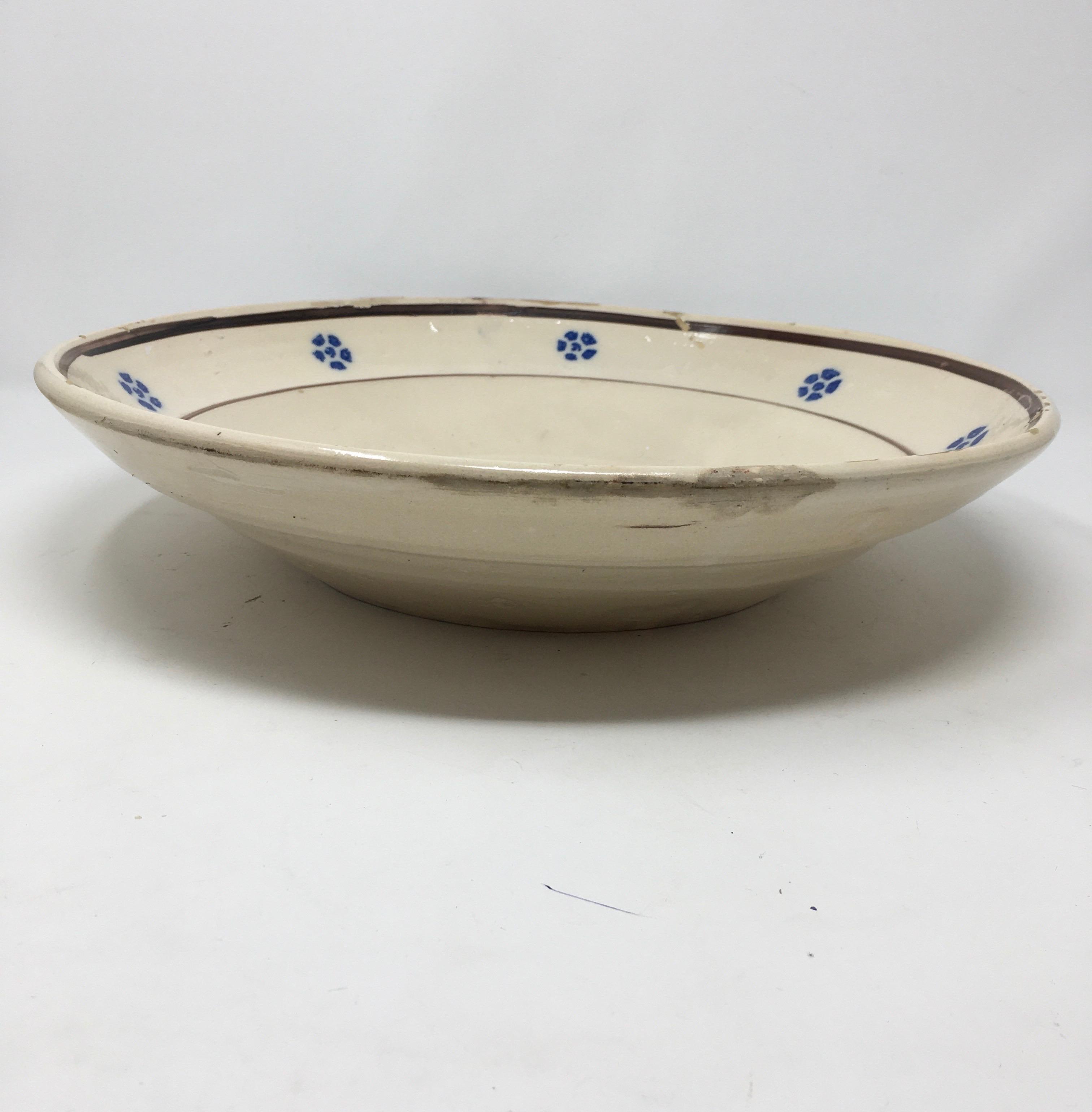 This hand painted Italian antique terracotta bowl is from the region of Puglia, Italy. The simple blue floral design around the rim is characteristic of this area. The shape is nice too. It is a bowl, but a very shallow one. This bowl shows wear