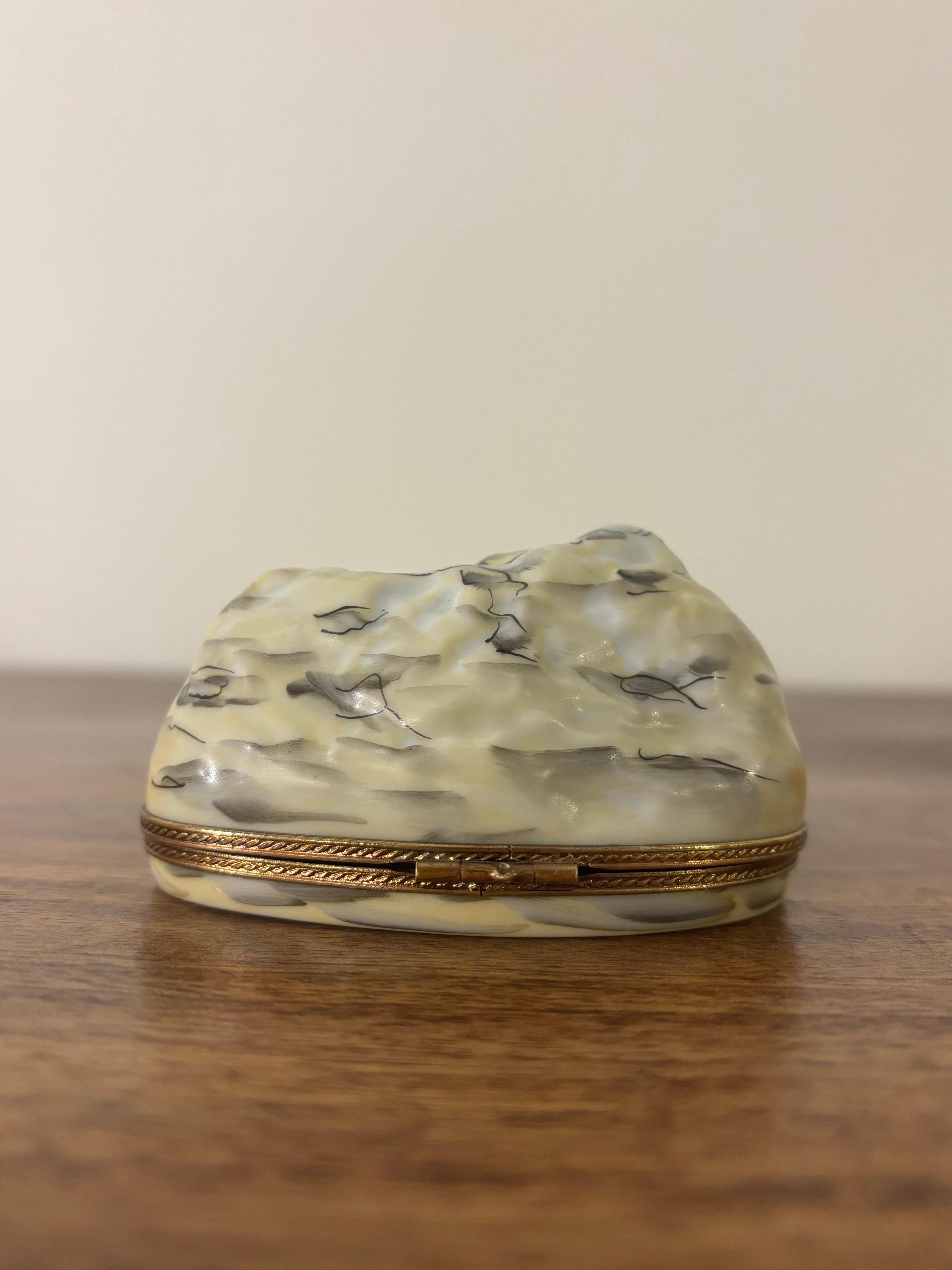 A charming and finely hand-painted Limoges porcelain trinket box depicting Mount Rushmore. Expertly detailed in the classic Limoges tradition, it captures the monument’s sculptural presence in miniature form. Hinged with gilt metal hardware and