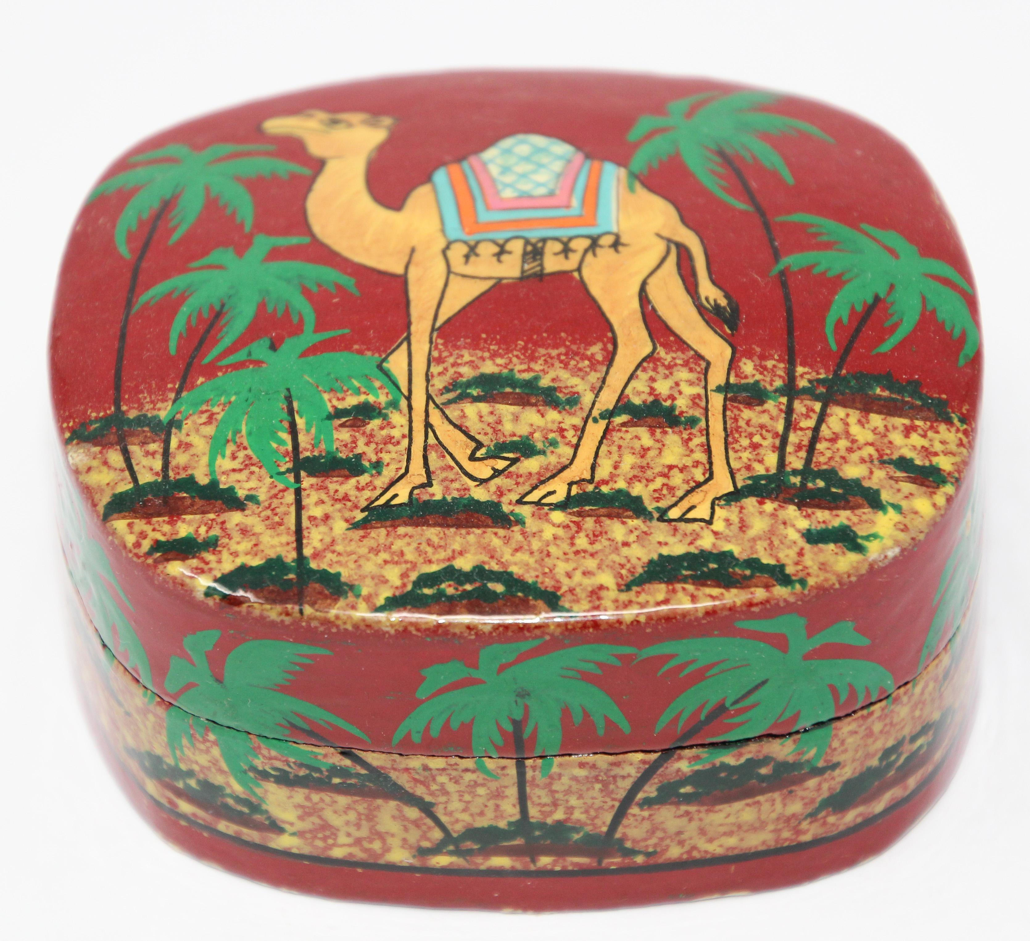 Hand painted Middle Eastern red and black lacquer box in rectangular shape with lid decorated a camel and palms.
Great decorative box with miniature painting of a camel in a desert oasis scene with palms on box.
Size is 3