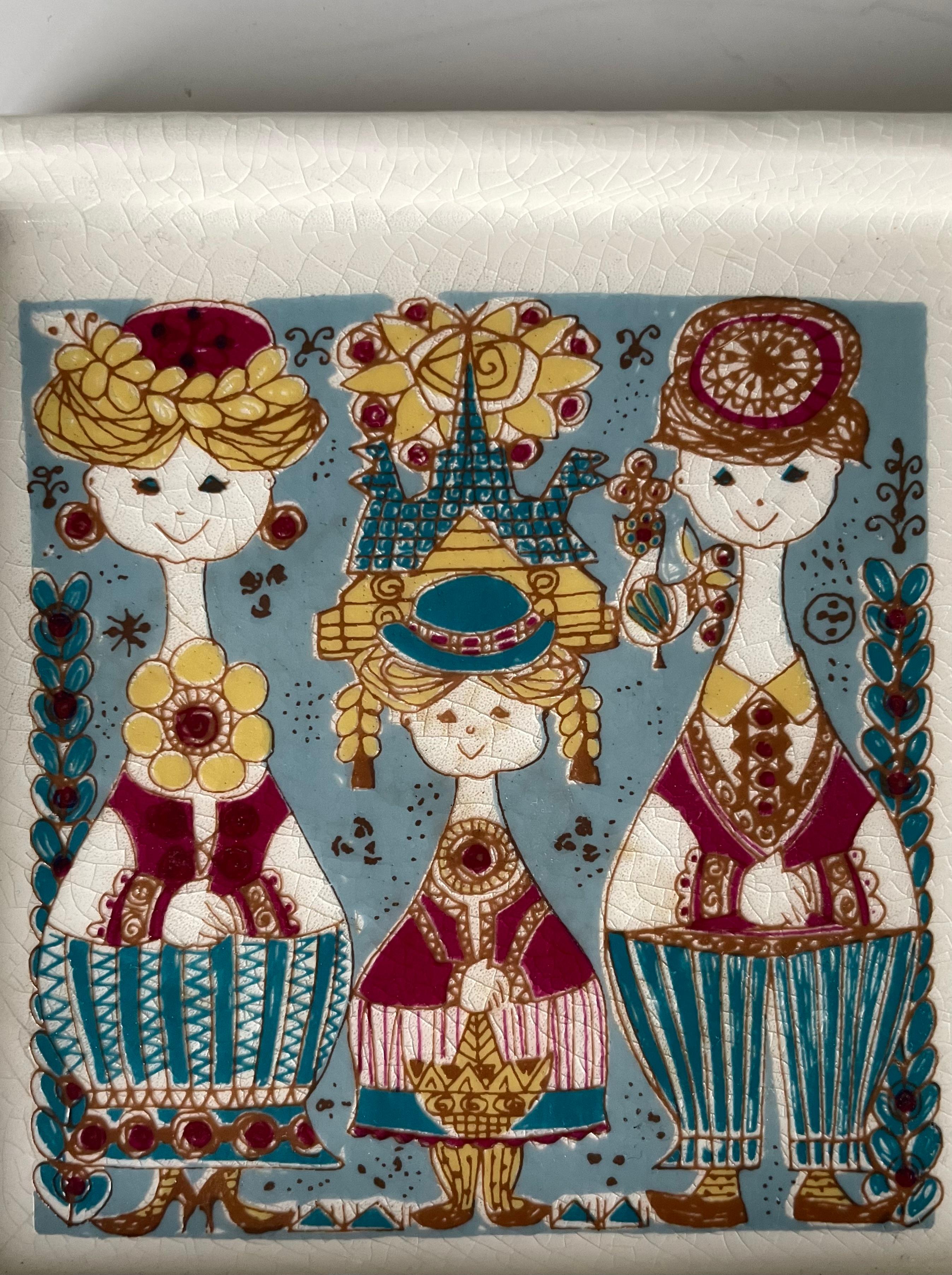 Square shaped multicolored decorative vide poche designed by Inger Waage (1923-1995) for Stavangerflint in the late 1950s-early 1960s. Three human figures stand smiling with colorful, patterned clothes and surrounded by flowers and organic shapes. A