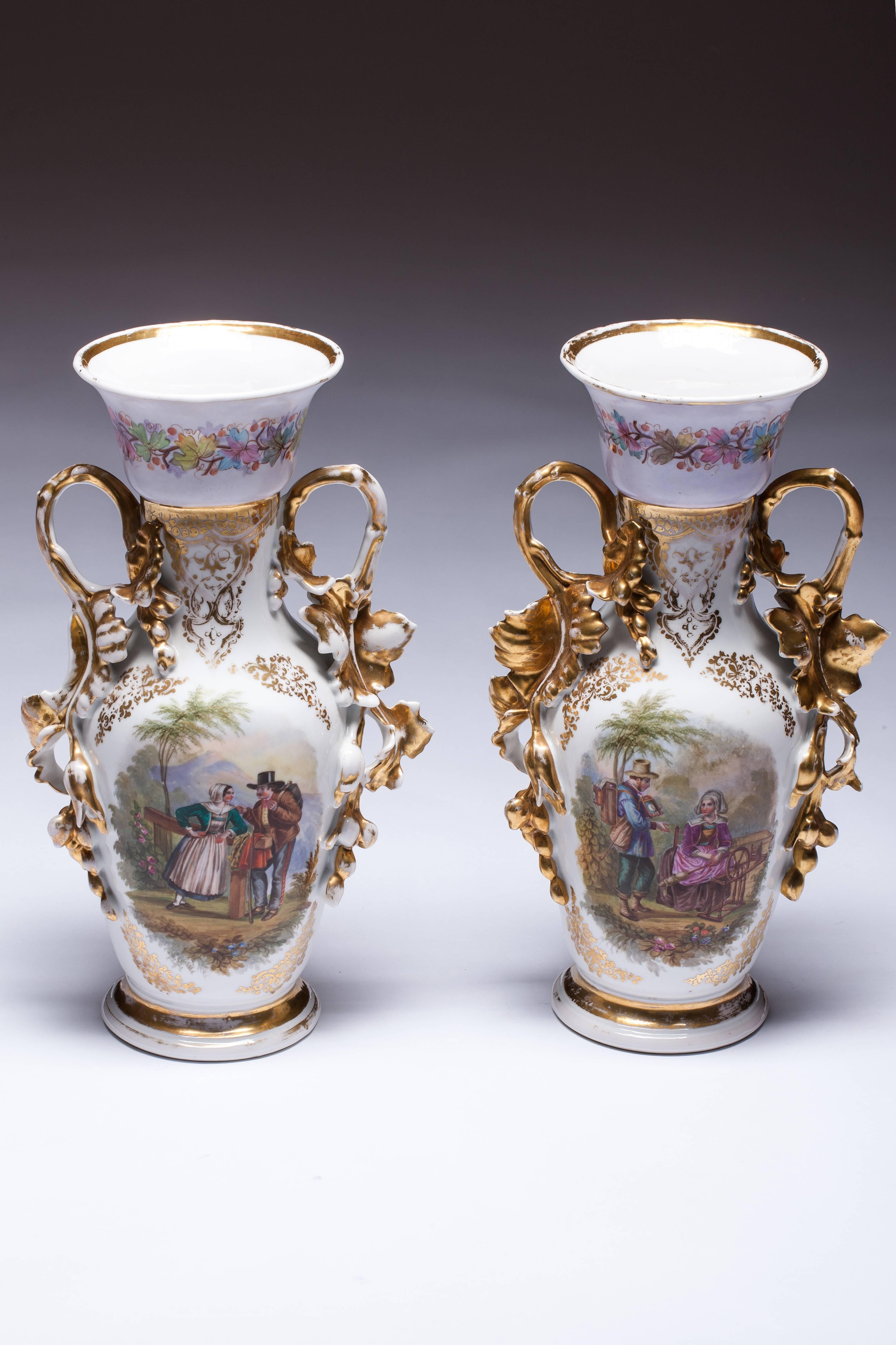Pair of hand-painted Old Paris vases on an alternating blue and white ground color. The vases feature hand paintings of floral decorations and country Family theme finished off with gilded ornate handles extending from top to bottom. Excellent