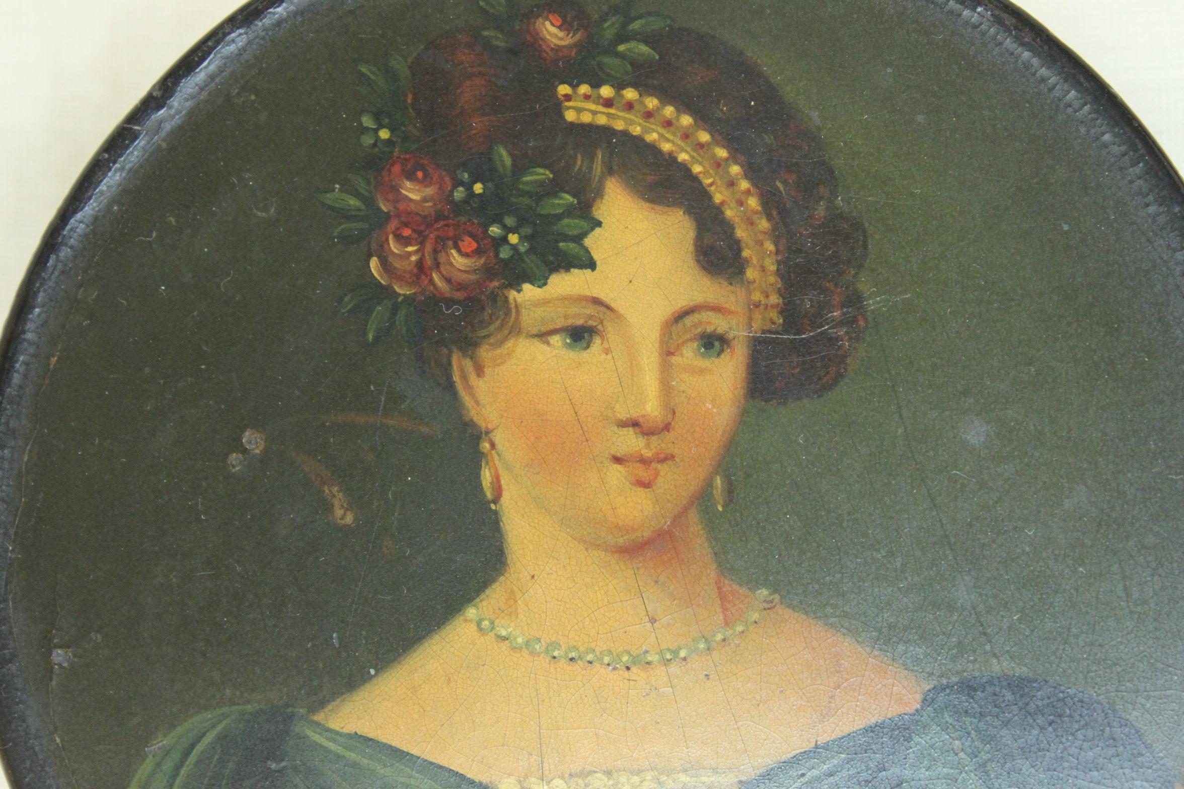 This papier mache snuff box is decorated with a hand painted portrait of a well dressed lady of the early nineteenth century. Possibly by Stobwasser of Brunswick in Germany it measures 90 mm (3.5 inches) in diameter and stands 20 mm (.75 inch) high.