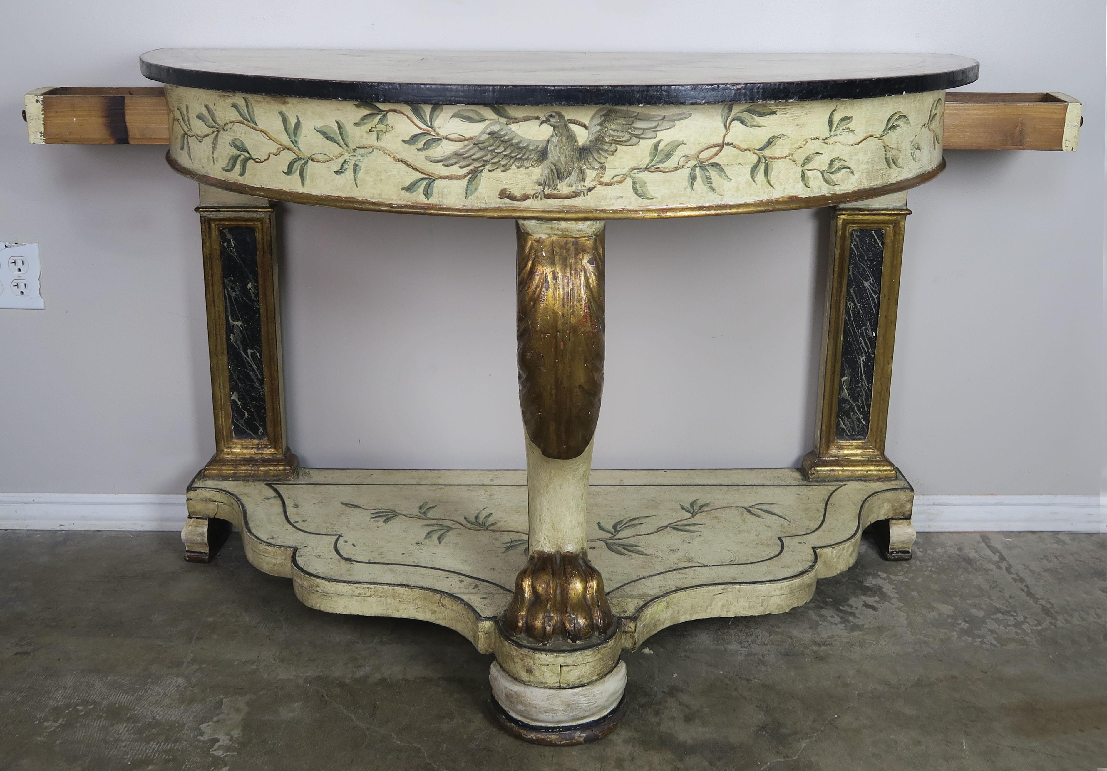 19th century English painted and parcel gilt demilune console table with serpentine shaped painted base. The table stands on three legs with a gilt wood let and paw in the front. Two small drawers at sides of console. Hand painted bird on the apron