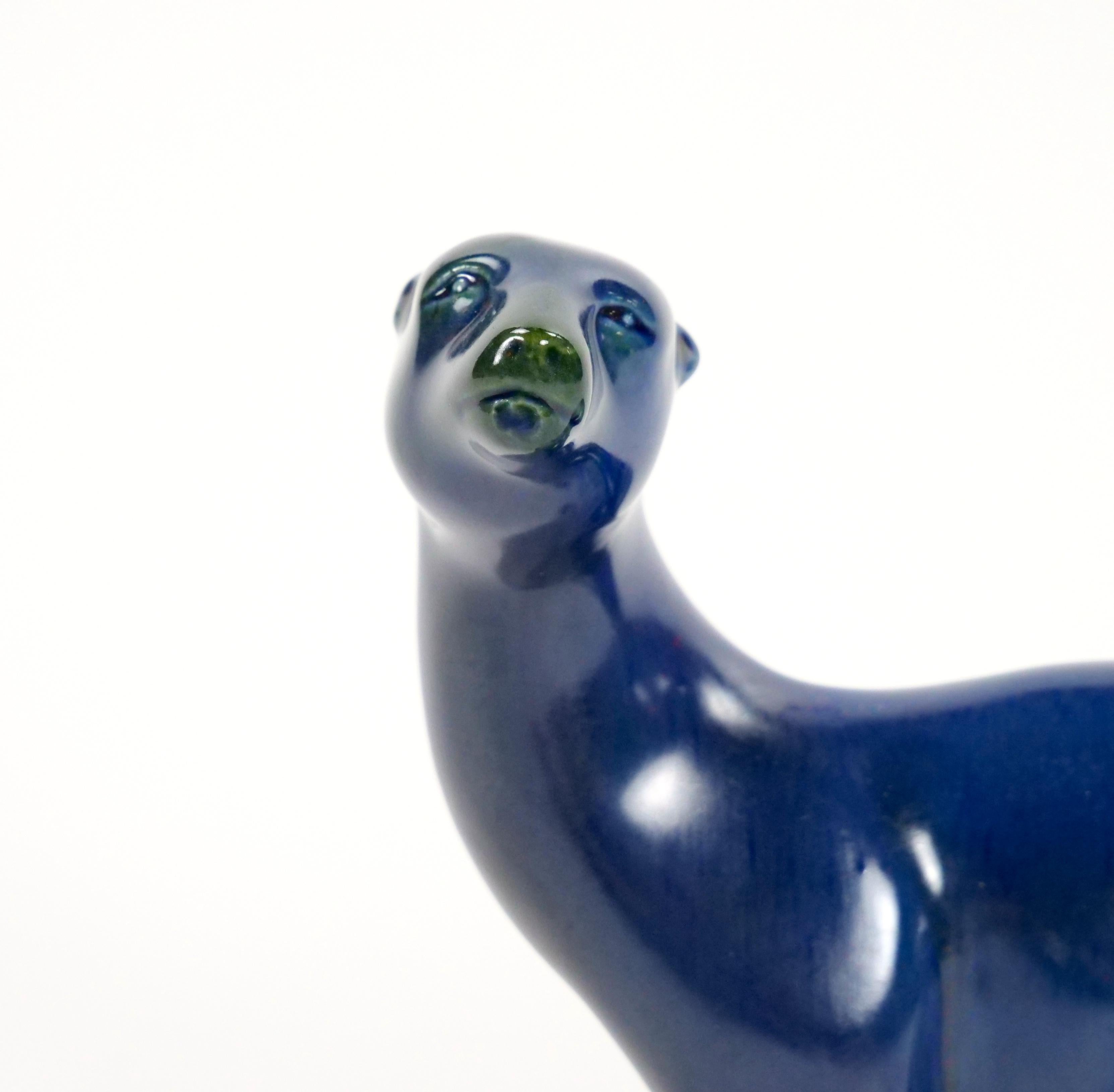 Esta extraordinaria escultura de porcelana pintada a mano de mediados del siglo XX muestra un llamativo oso polar, meticulosamente elaborado con un arte excepcional. La figura está adornada con ricos tonos azul cobalto, complementados con un brillo