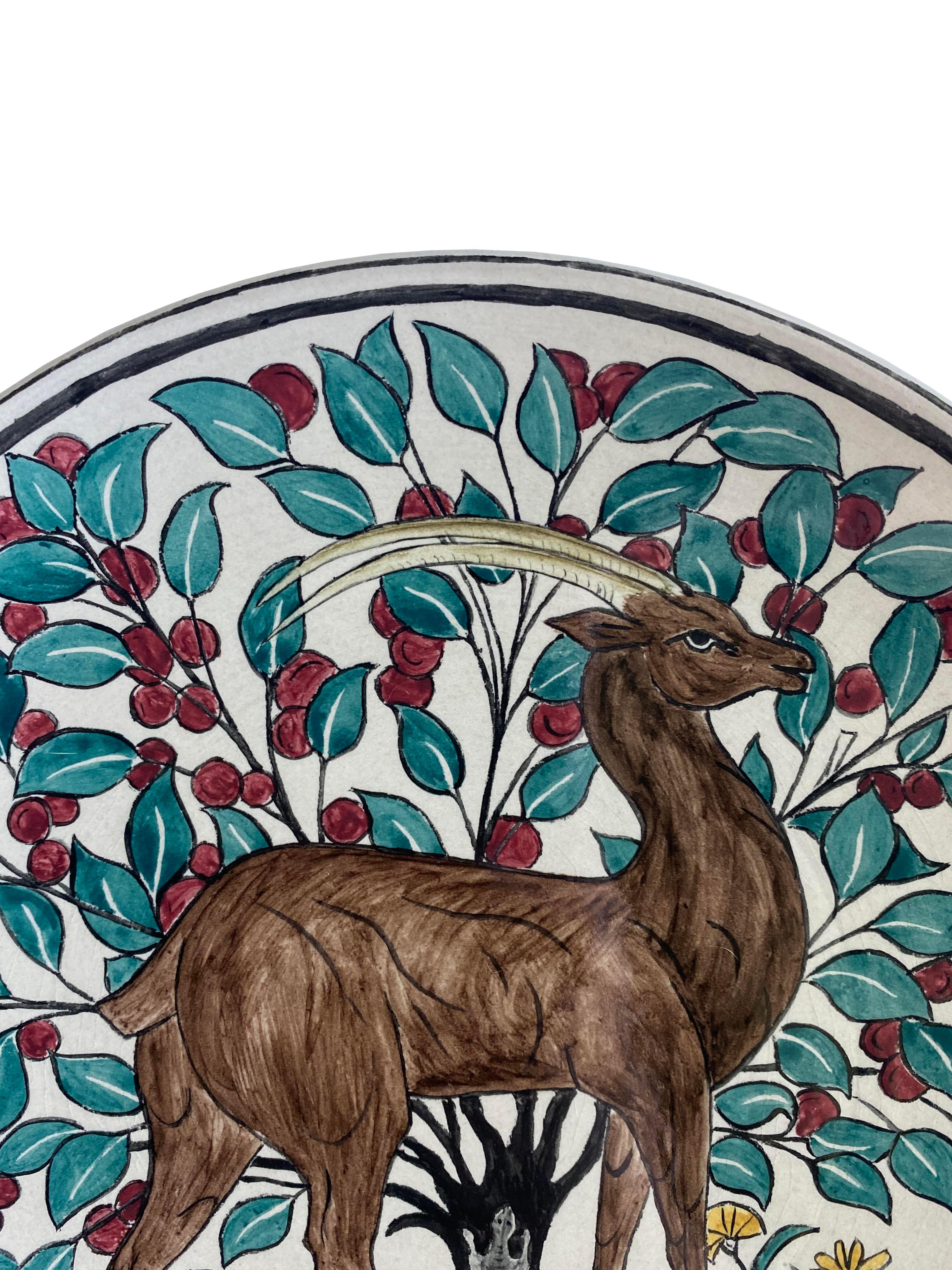 Un cautivador plato de porcelana pintado a mano, una auténtica joya para coleccionistas y aficionados. Representando una cabra montés que navega graciosamente por un exuberante paisaje rebosante de vida, esta pieza resuena con la belleza de la