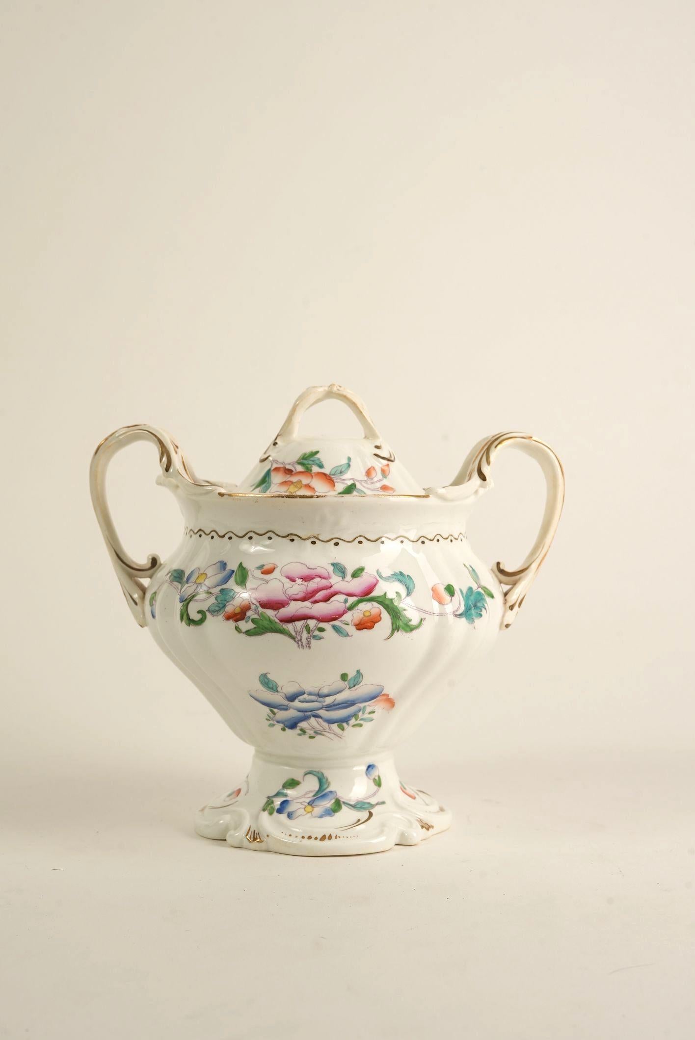 What makes this piece unique is its remarkable combination of ornate form and delicate hand-painted florals — a true testament to early 20th-century European porcelain craftsmanship. With its graceful curves, elevated pedestal base, and looping