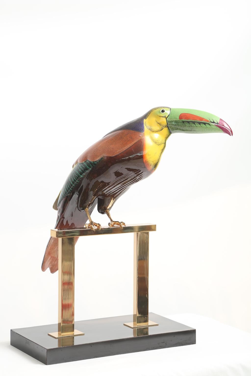 Toucan, designed by Mangani for Oggetti, beautifully hand painted in rich colors, on gold gilt talons, set upon a perch of polished brass, on a lacquered plinth. Base measures 13.5 in. x 7.25 in. 

Stock ID: D1662.