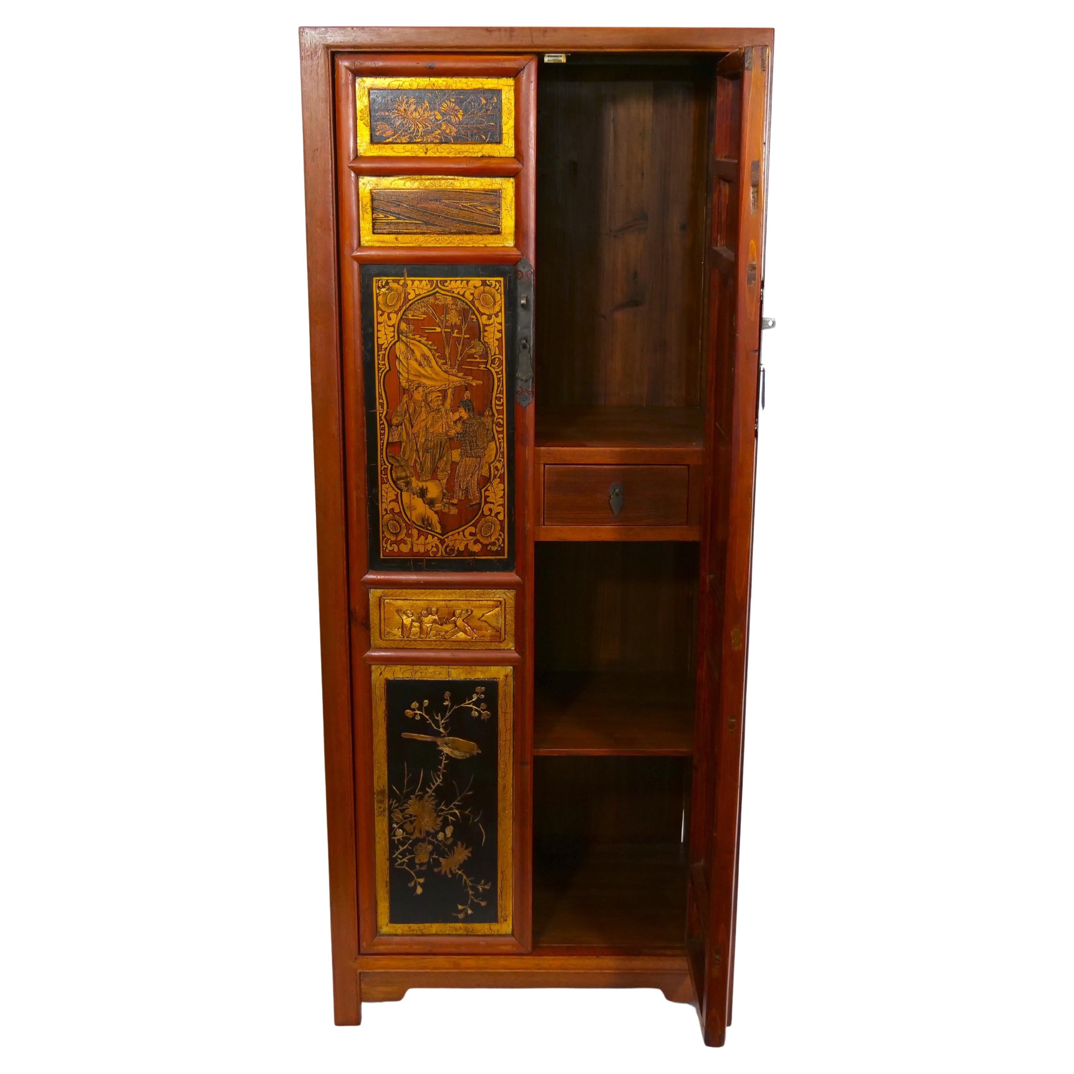 Mid-20th century hand painted red / gilt lacquered wood chinoiserie display cabinet. The cabinet features two front door and two interior pull drawer with different hand painted gilt gold chinoiserie scene, resting on four feet. The cabinet is in