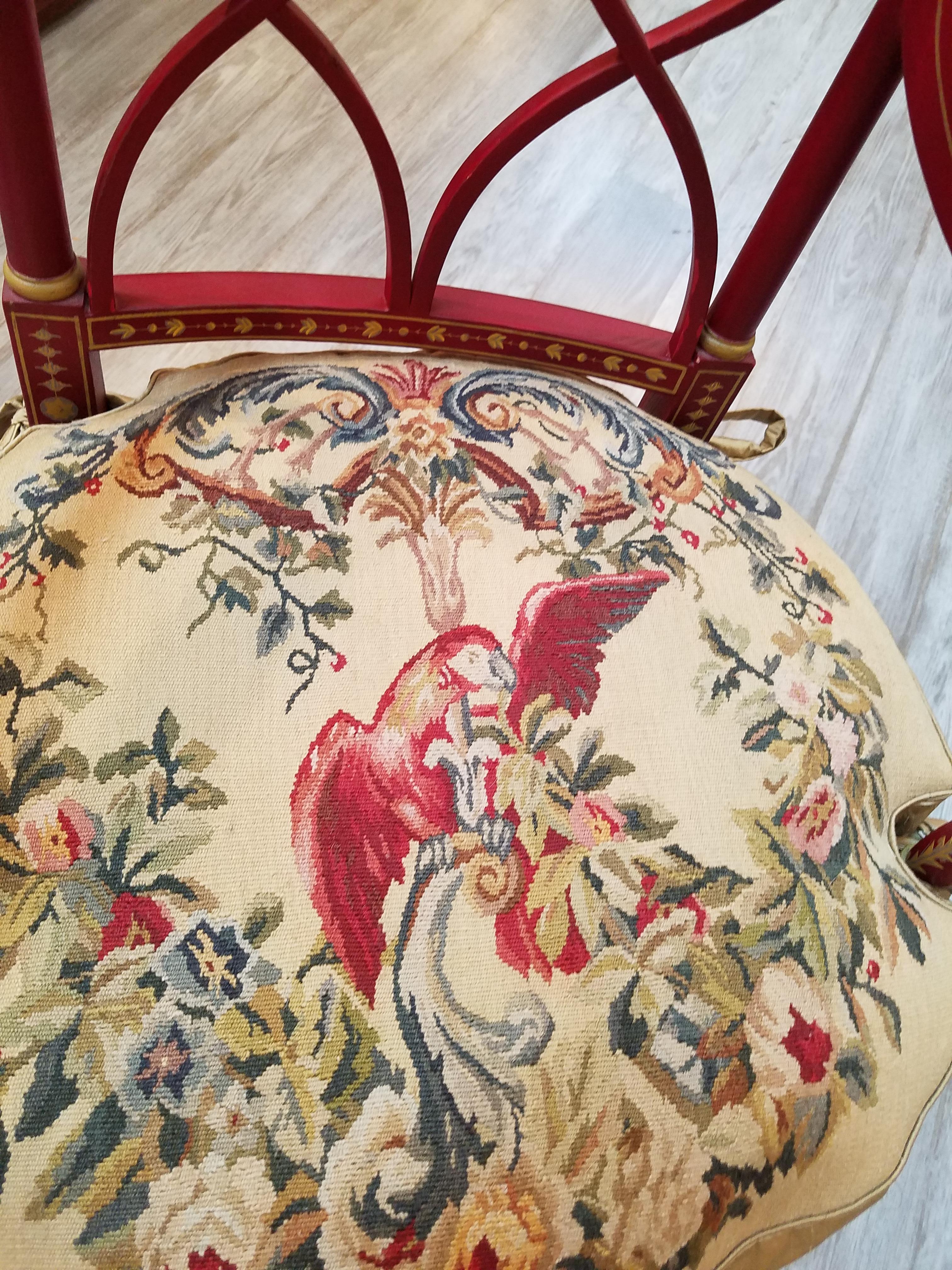 Elegant hand painted Regency style armchair with wool needlepoint seat cushion. The Chinese red background with gold hand painted details all-over. The cushion with a hand done needlepoint and silk backed seat cushion depicting a red parrot with