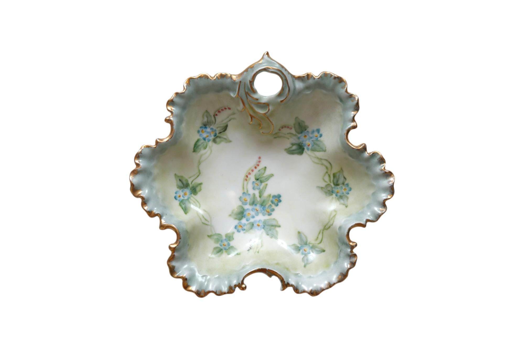 Plat en céramique de style Rocaille peint à la main. Les bords festonnés en forme de ruban sont garnis de dorures, et une poignée percée est pressée avec une forme d'acanthe asymétrique. Le plat est décoré de gerbes de myosotis et de digitales, et