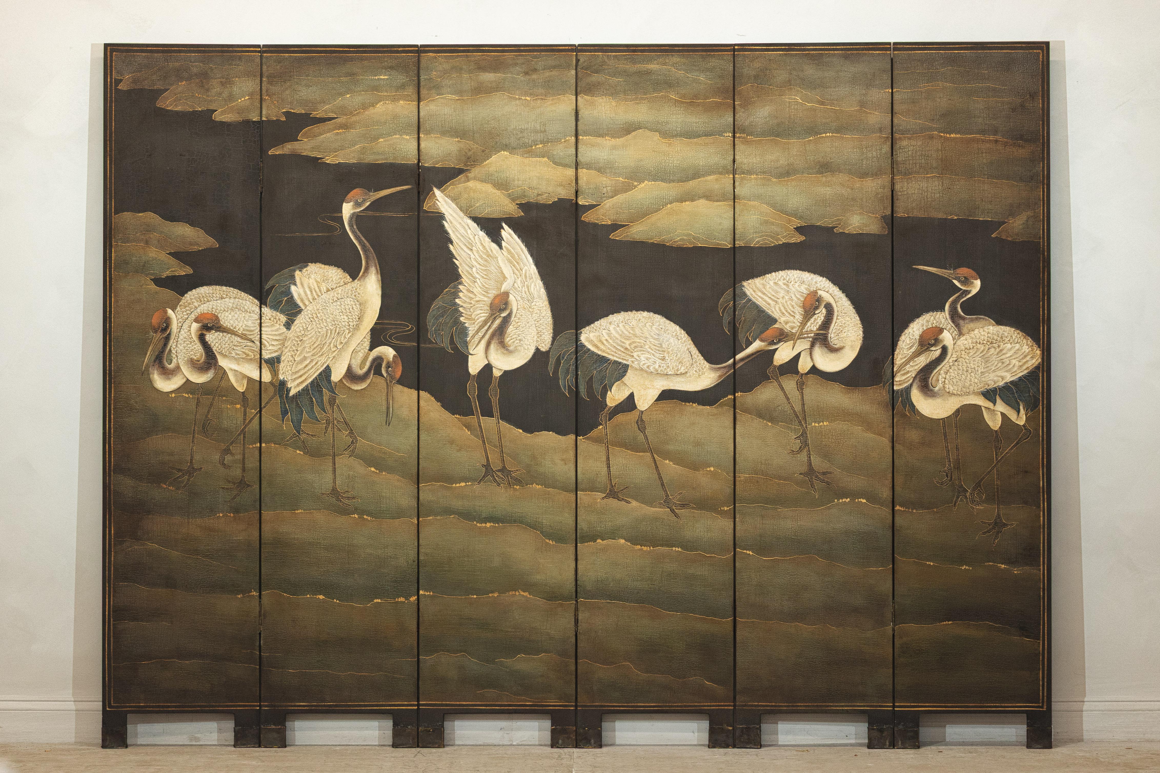 A six-panel vintage Chinese screen hand-painted with a serene and balanced composition of red-crested cranes set against a stylized landscape. Presented in subdued tones of ivory, ochre, sage, and charcoal, the imagery reflects traditional East