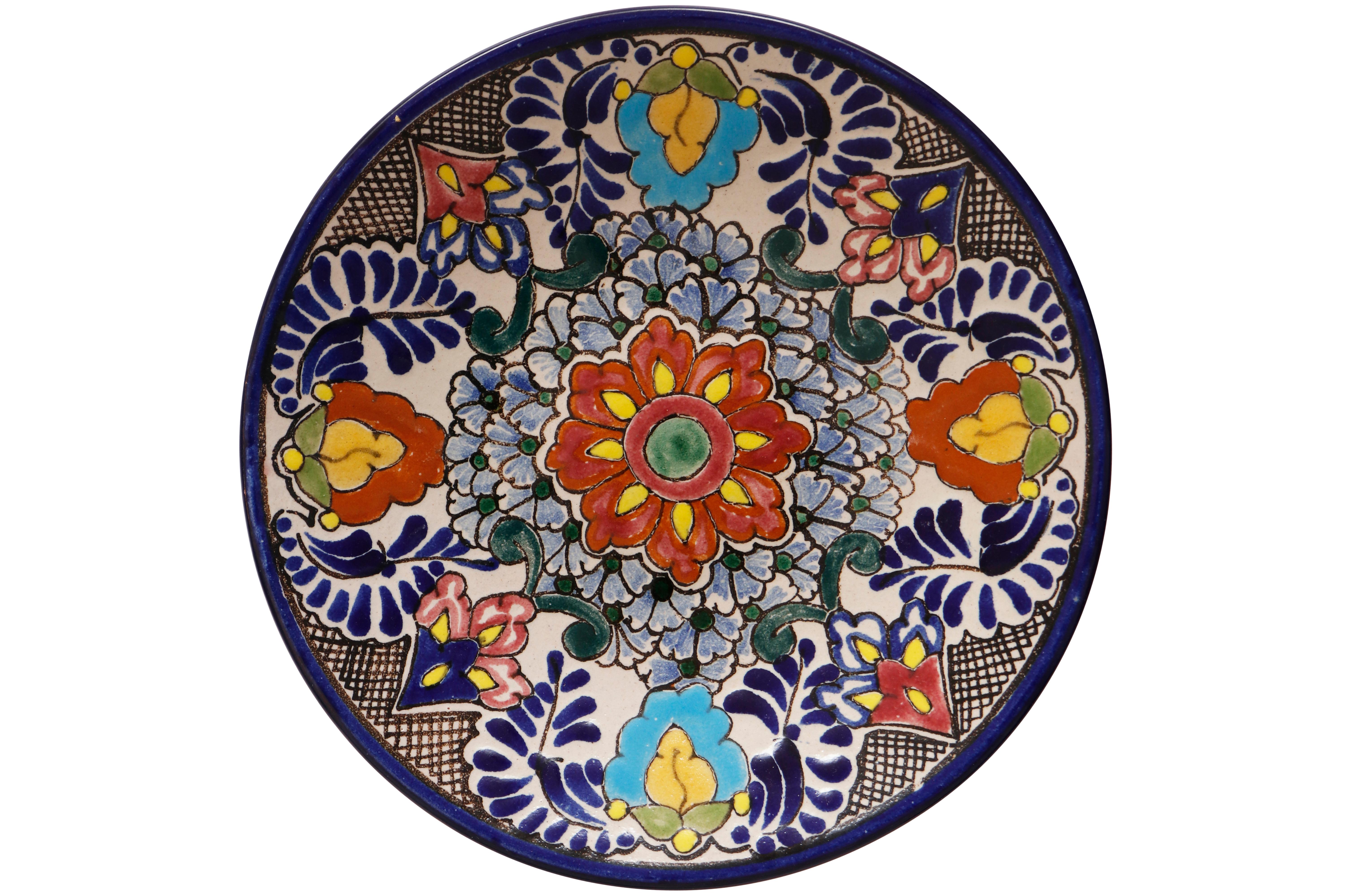 A set of eight hand painted Talavera plates. Each plate is decorated with a different raised floral motif in bold colors, finished with a cobalt blue rim. Plates are signed “Talavera, Loza Blanca, Puebla Mexico” in the back with holes for hanging.