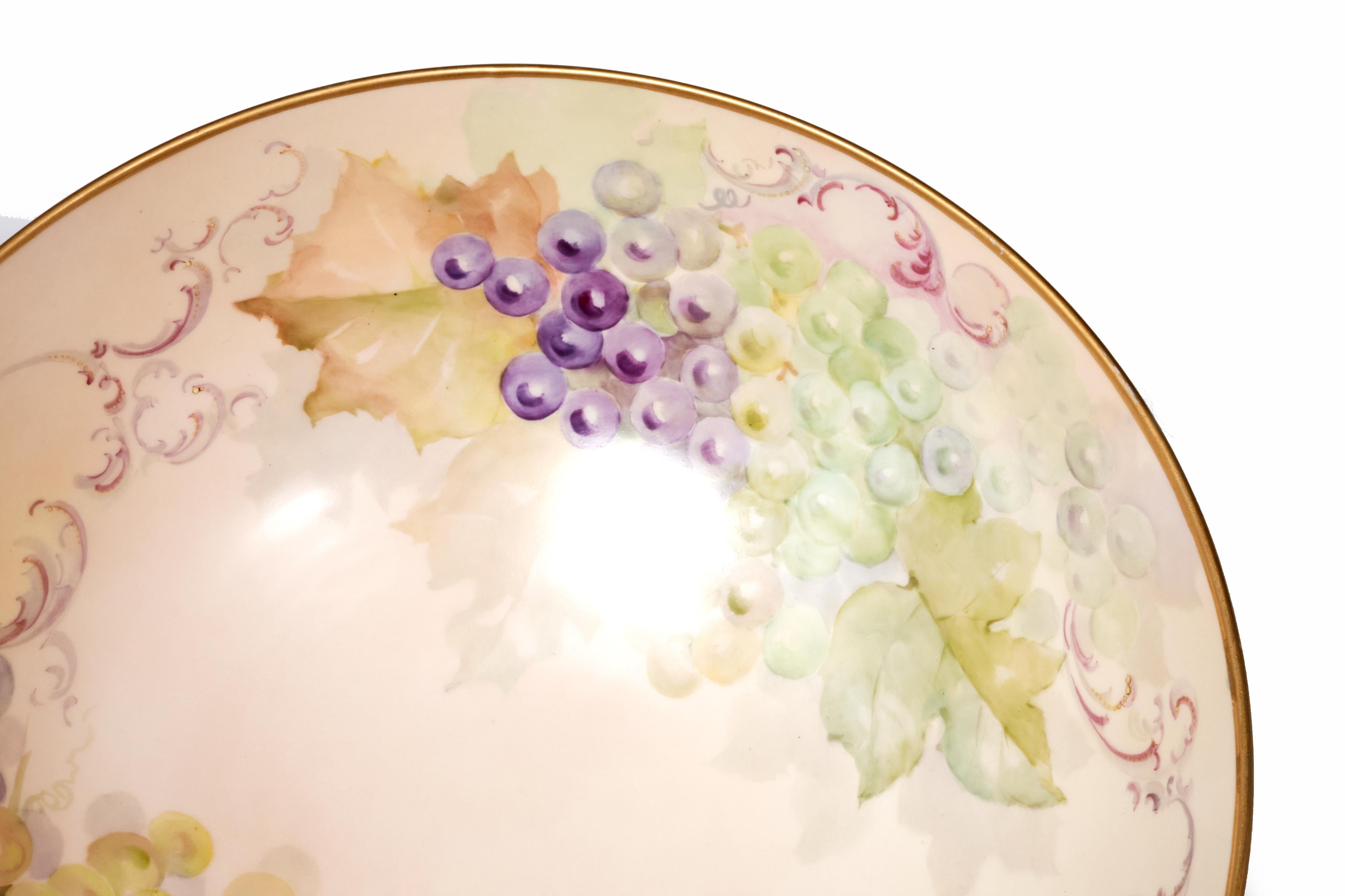 Rare French hand painted porcelain punch bowl with footed porcelain base. Bowl is beautifully decorated with grapes on the interior and florals on the outside. Condition is excellent without chips, cracks or repairs. There is some wear on the gold