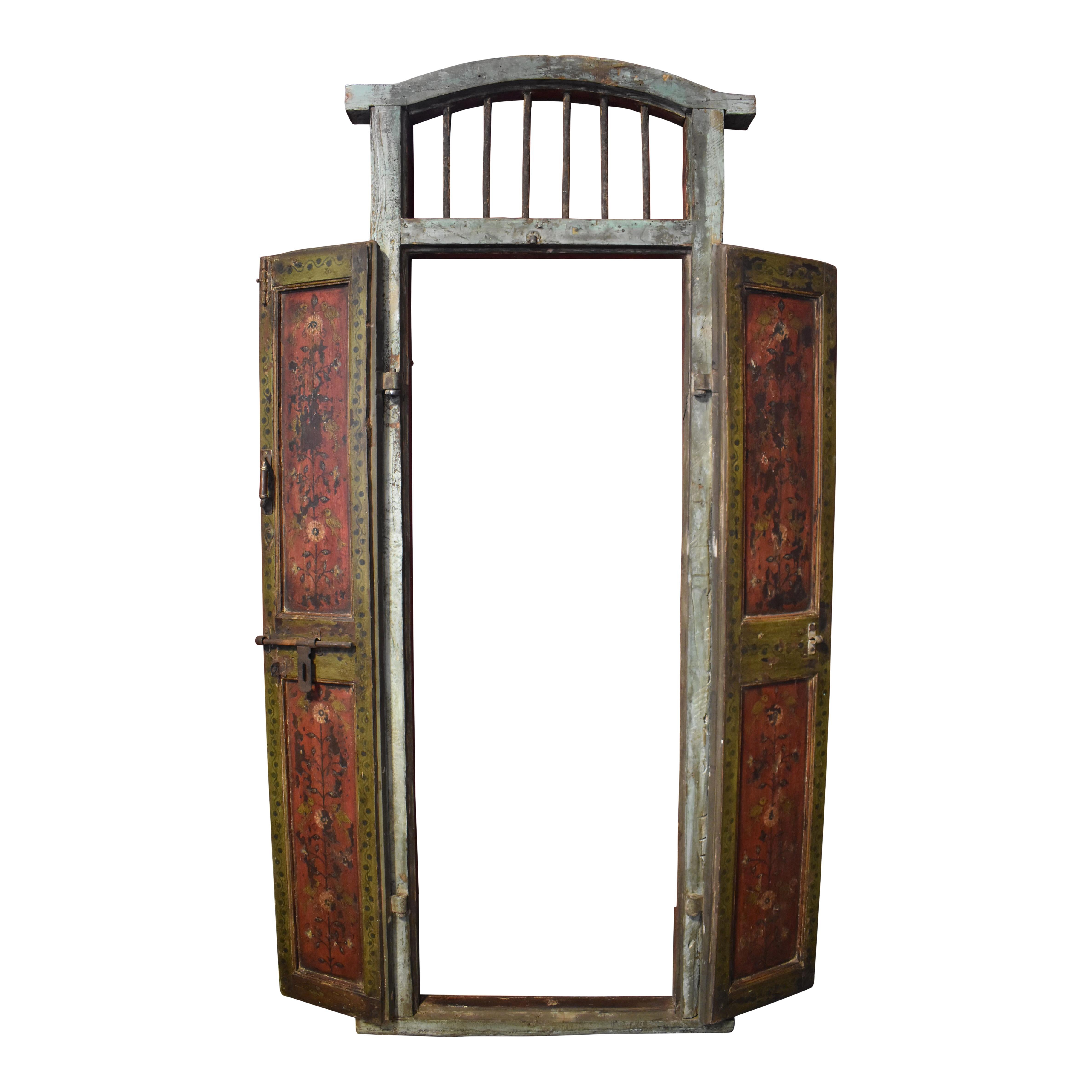Hand-painted in the folk art style that is typical of the Northern European area of the Netherlands and Belgium, these charming doors in their original frame feature a floral and fowl motif. A framed arched transom with six vertical spindles crowns