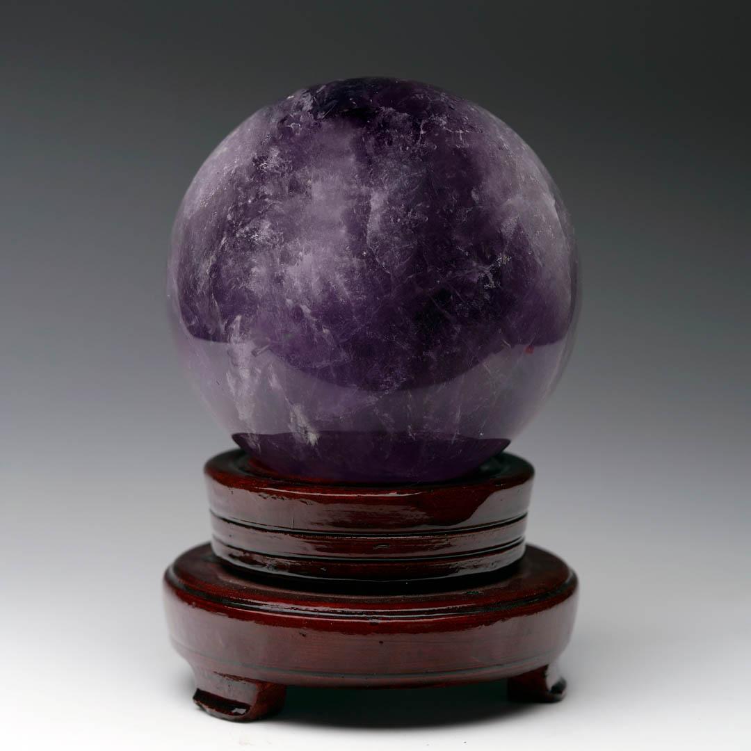 Eleva tu espacio con esta esfera de Amatista natural, que muestra fascinantes tonos arremolinados de morado intenso y lavanda translúcido. Pulido a mano por expertos hasta conseguir un acabado liso y muy brillante, este orbe de cristal de amatista
