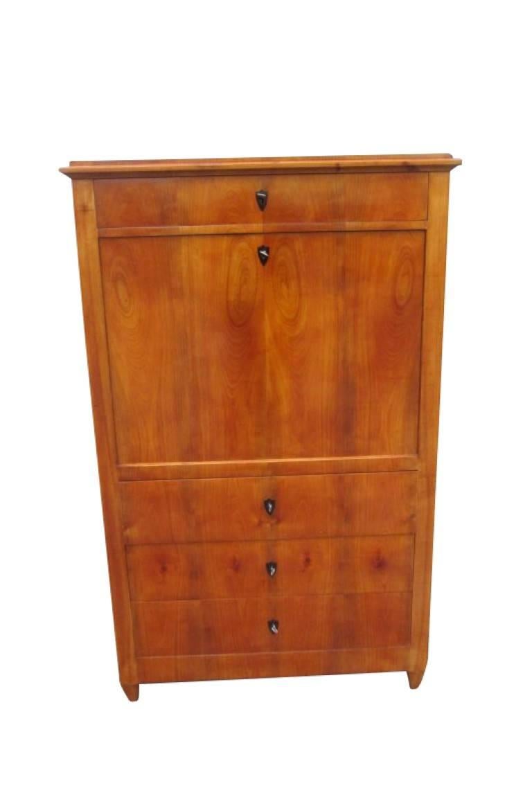 A Biedermeier secretary from circa 1830. This piece contains several wood types which were processed differently. The body is made of softwood with a cherry tree veneer inlaid. It has four large drawers which all run very well and are clean inside.