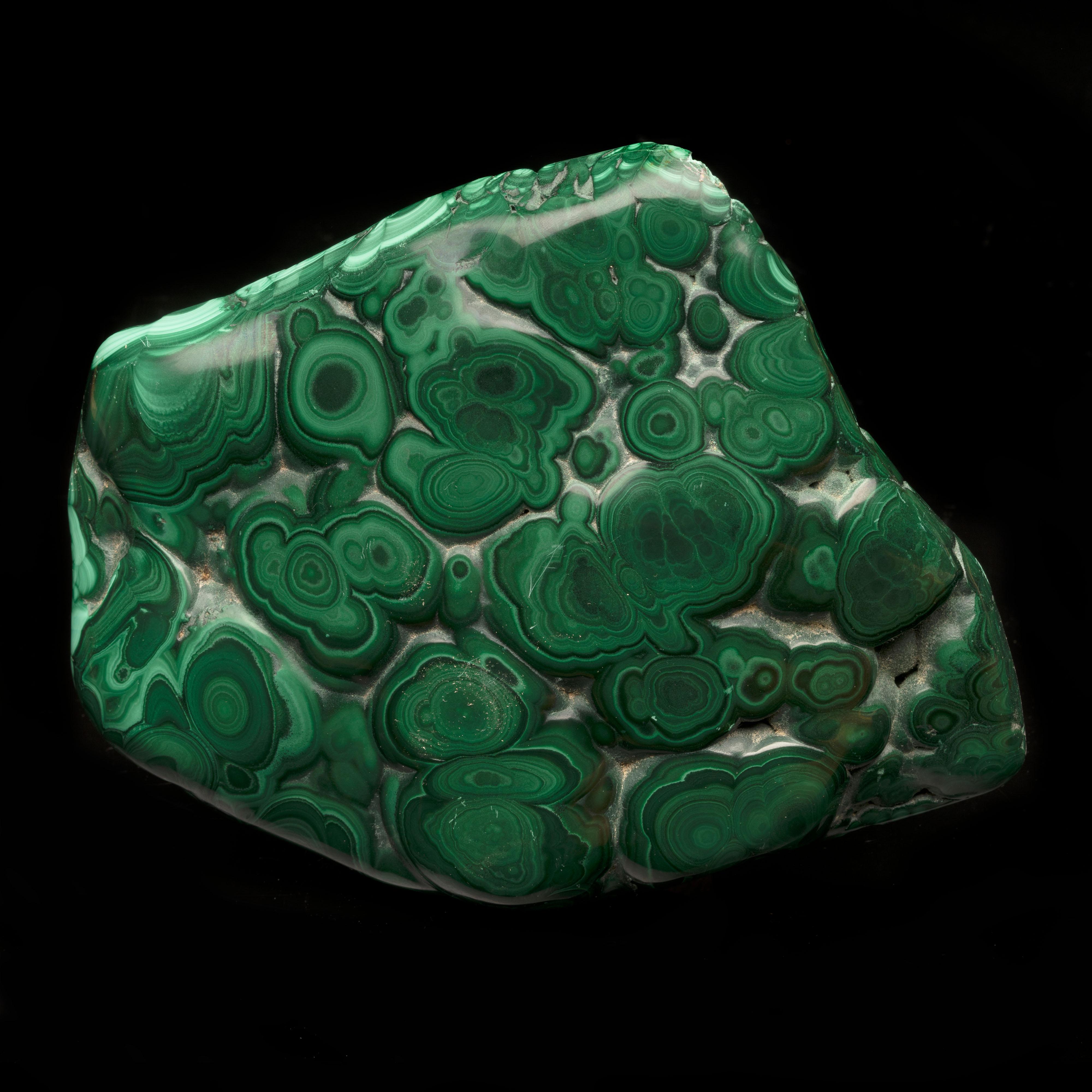 This expertly hand-polished top grade 4 lb malachite freeform from the DRC features excellent color and an abundance of well-defined bullseyes. Malachite is a lusciously hued, bright and dark green banded copper carbonate mineral that often grows