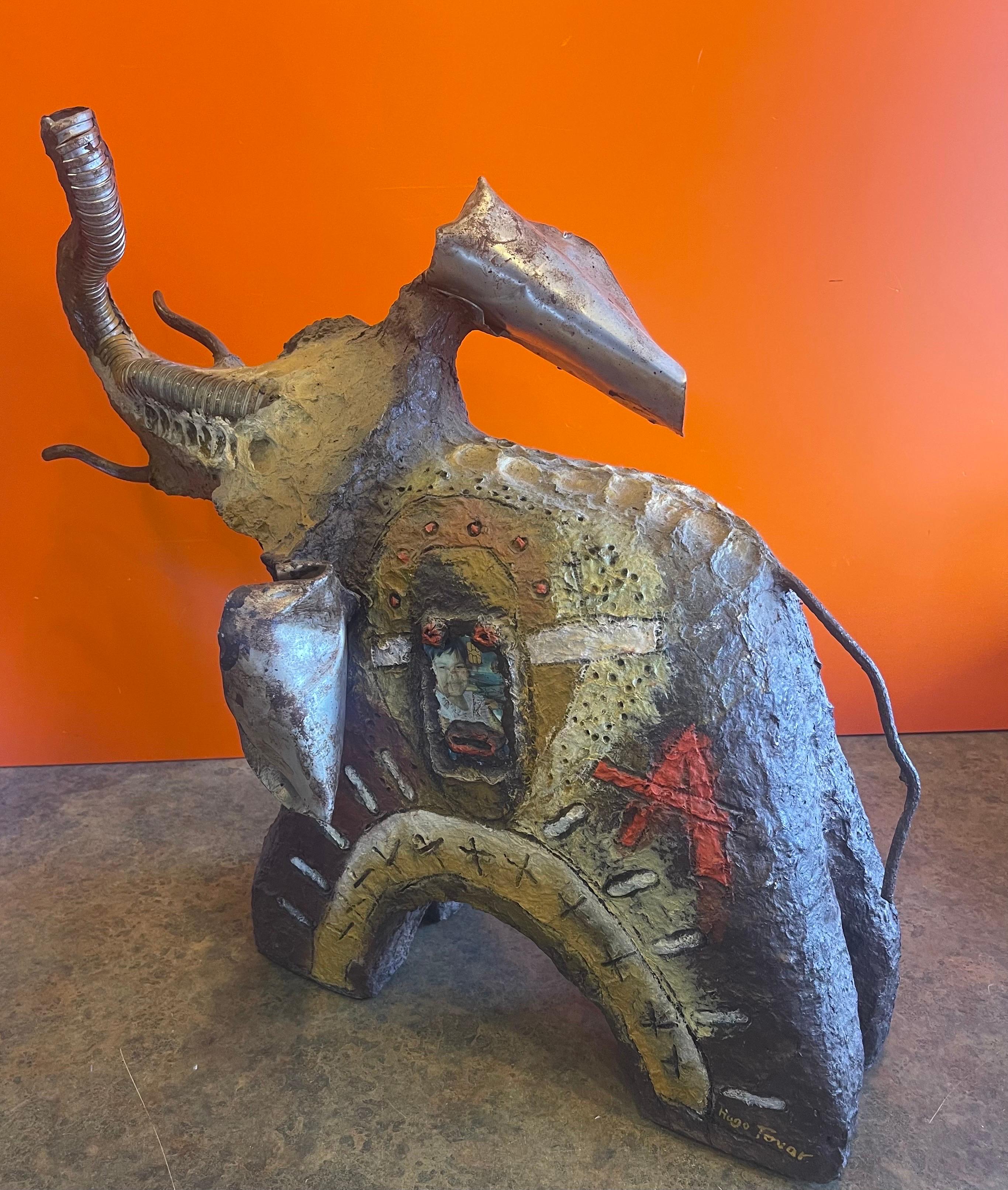 Hand sculpted modernist elephant assemblage sculpture by Hugo Tovar of Mexico, circa 2000. It portrays an elephant with trunk up; crafted and assembled from recycled materials including paper, various objects, metal, varnishes and acrylic paints.