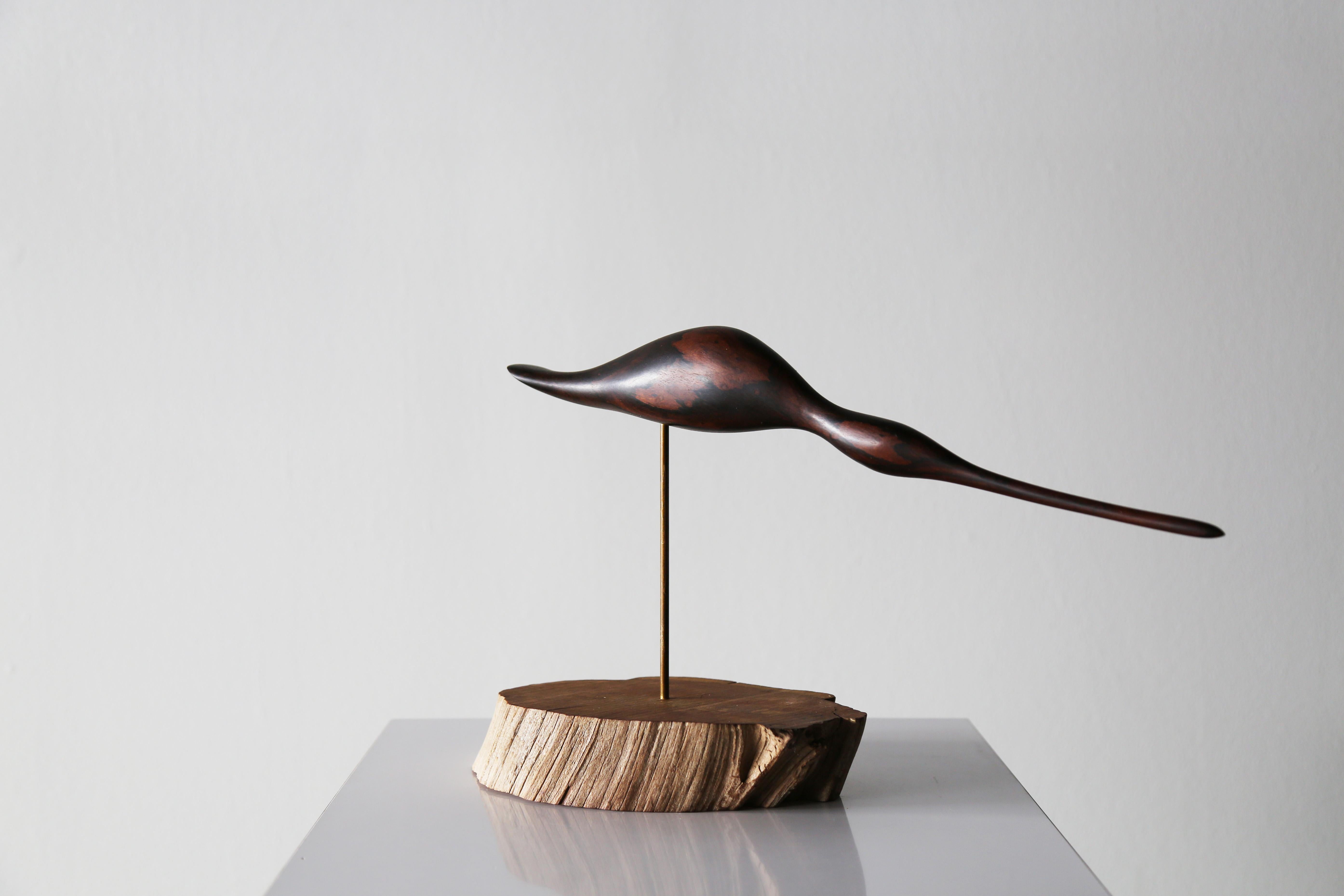 A vintage rosewood shore bird, perched on a live edge wood pedestal. The shorebird can pivot on the dowel to face in different directions. Rosewood is a protected species and was banned from importation in to the United States in the late 1970s and