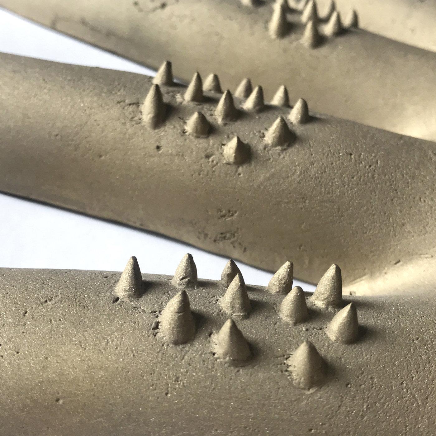 This work is crafted from brass using a lost wax casting technique, representing an image from the artist's memory and a vital fragment of the human form. Prominent spikes represent tiny hairs and create a tactile effect, bringing depth and texture