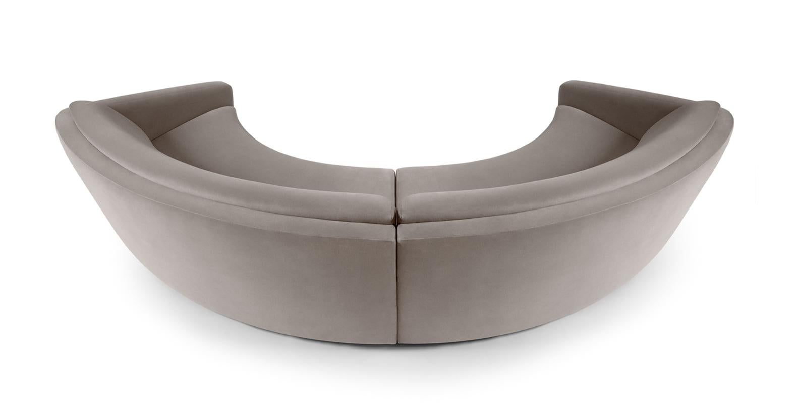The handmade sofa is the representation of magnetism. Featuring tailored upholstery in light grey cotton velvet and a stylish brushed brass footer, it is masterfully crafted with an emphatic, yet elegant, curved contour. The sofa is a statement