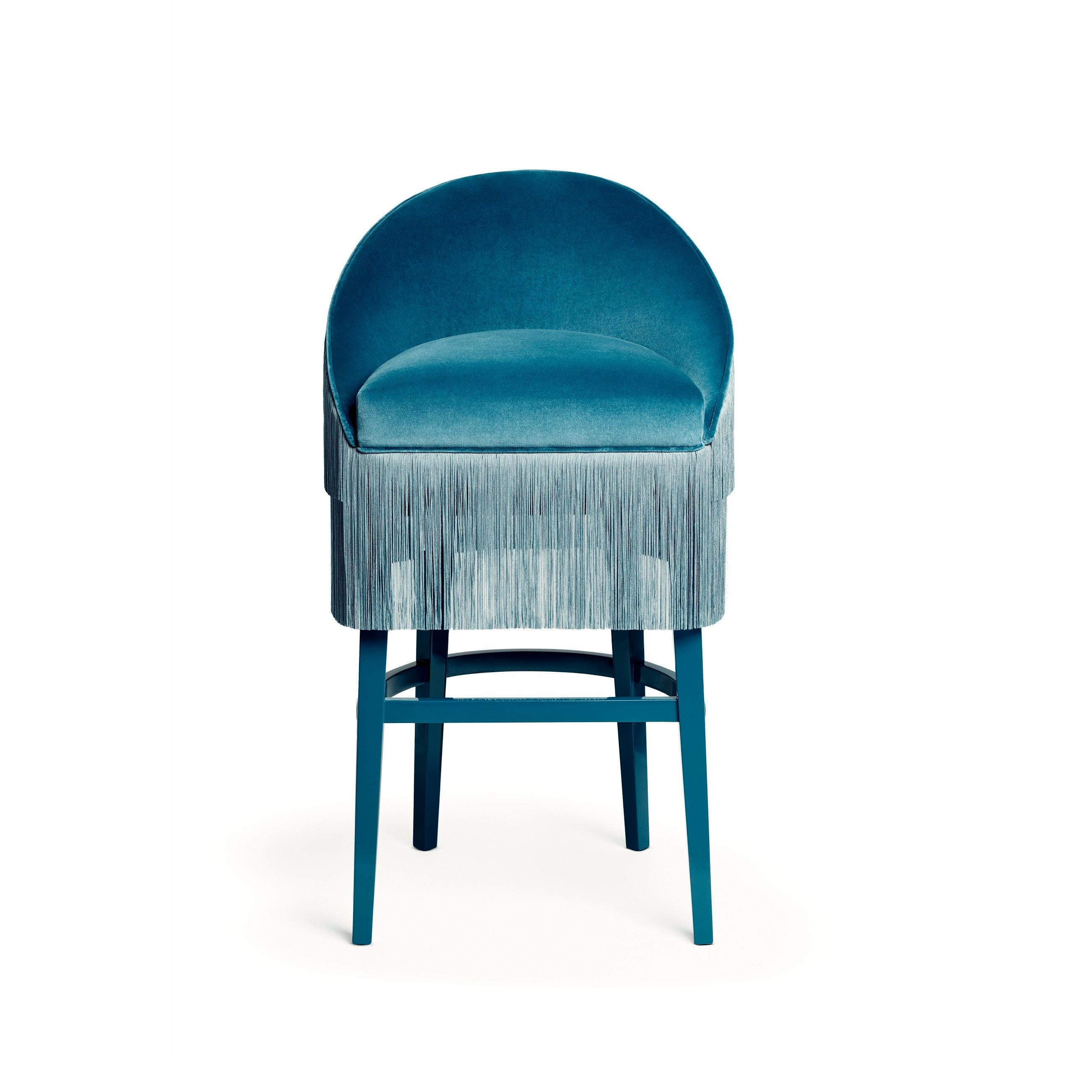 The handmade barstool draws on the signature fashion theme, ruffling the scene and inviting guests with its fun and flirtatious feel. Featuring three layers of fringes that run along the front and reverse of the wide seat, set against a curved