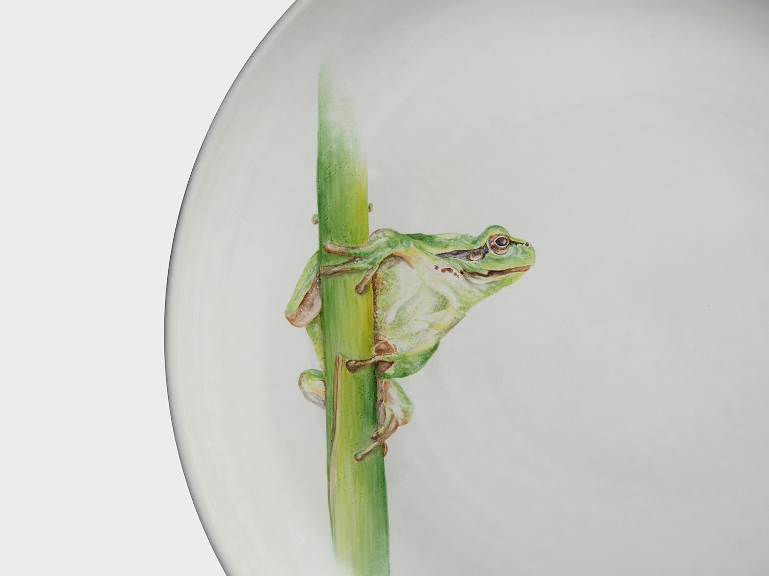 This hand thrown centerpiece plate was turned in Porzellan Manufaktur Nymphenburg in the majolica department freehand on the wheel. The foot has a black engobe and the white glaze reaches the edge of the black.
Our painter has given it life with an