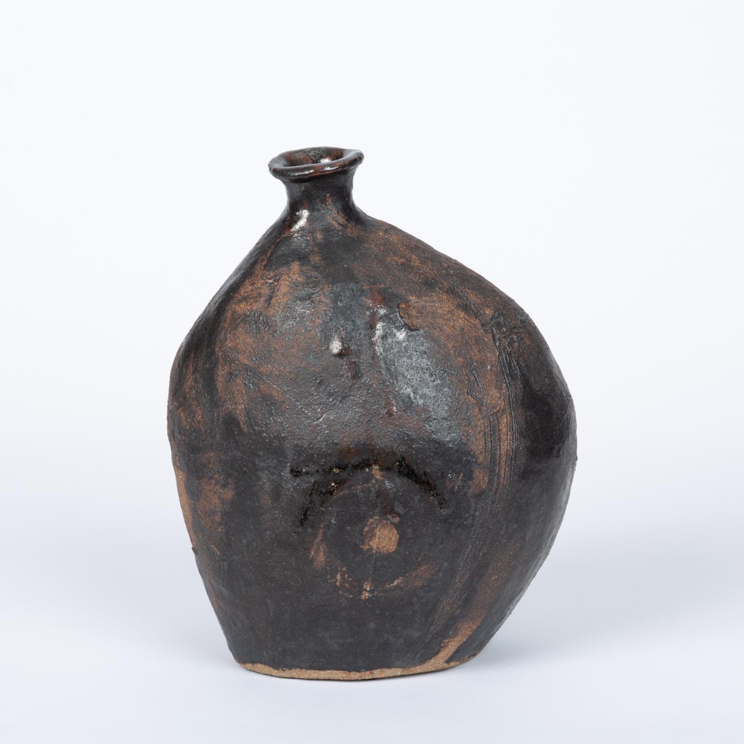 A Studio Pottery ceramic vessel in glazed stoneware. The pieces features an ebony matte glaze lightly applied on the body of the vessel with white glossy glaze accents, while the bottom is left unglazed in the natural stoneware clay. Signed 