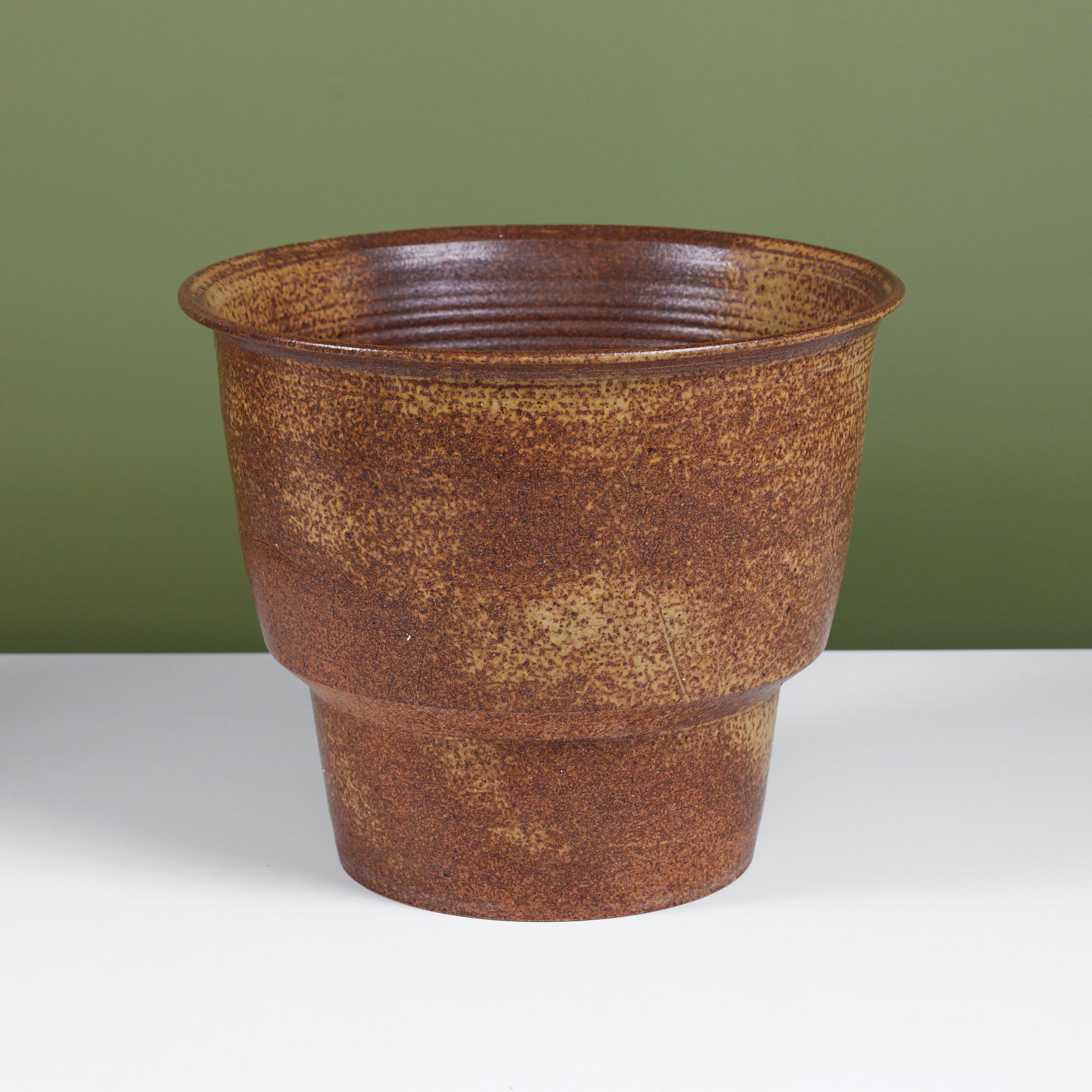 Hand thrown stoneware planter. This planter features a golden brown and yellow speckle glaze both on the exterior and interior. The planter tapers towards the bottom and has a flat lip around the top.
Signed.

Dimensions
14