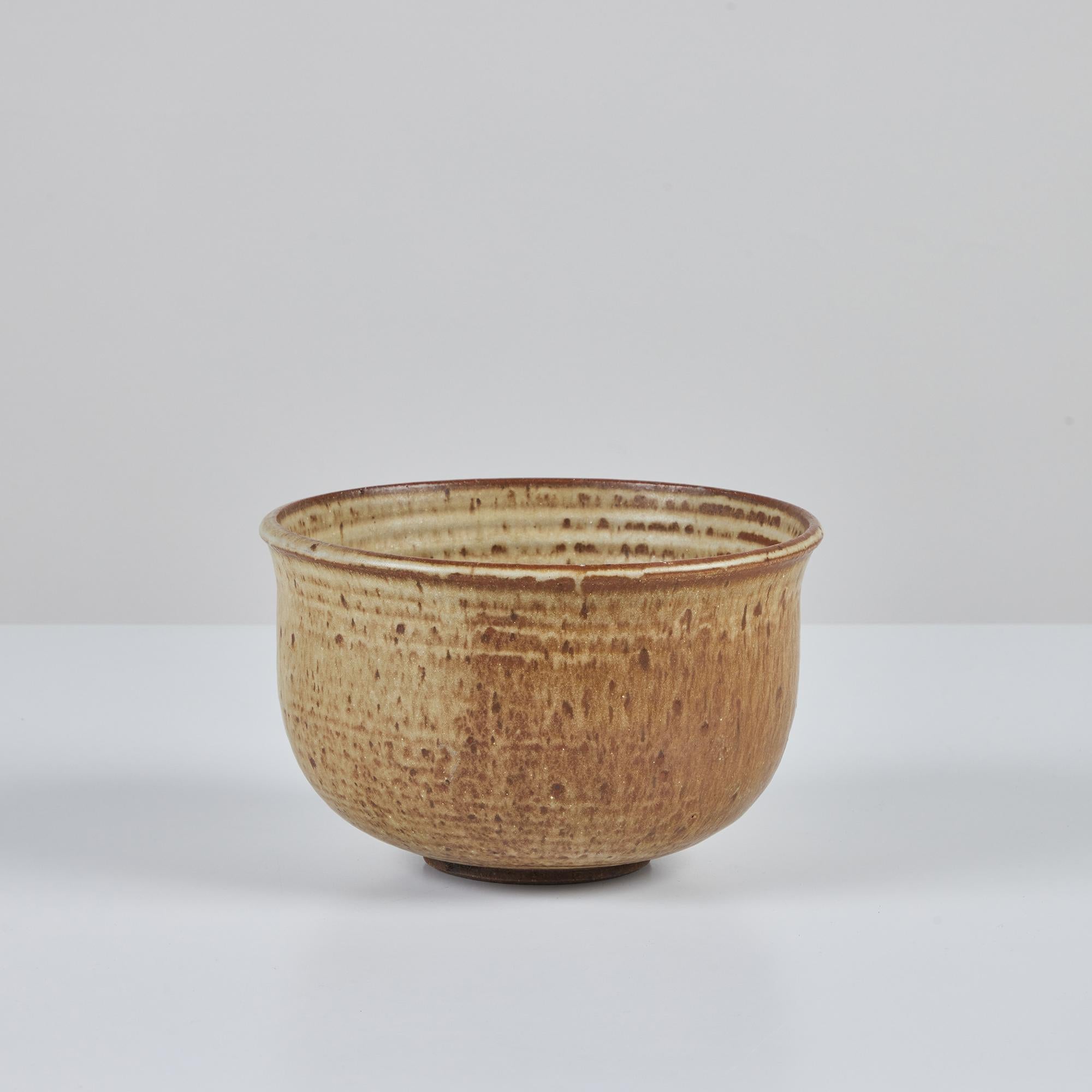 Hand thrown studio pottery planter. This example has a flared lip and round body. It is decorated with with a two tone sand and cinnamon speckled glaze all over. The interior showcases the finger grooves from the wheel on the vessels