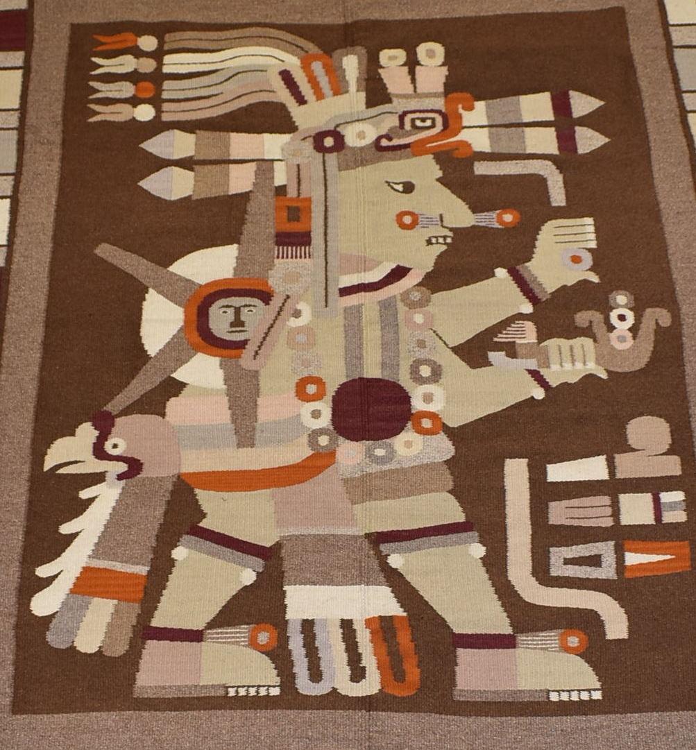 Large hand tied wool rug in shades of browns, orange, burgundy, and creams. This rug appears to be of Montezuma, the Aztec Emperor, depicted with a star, a pipe, an eagle, and other objects. South American style. Great condition with no damage.