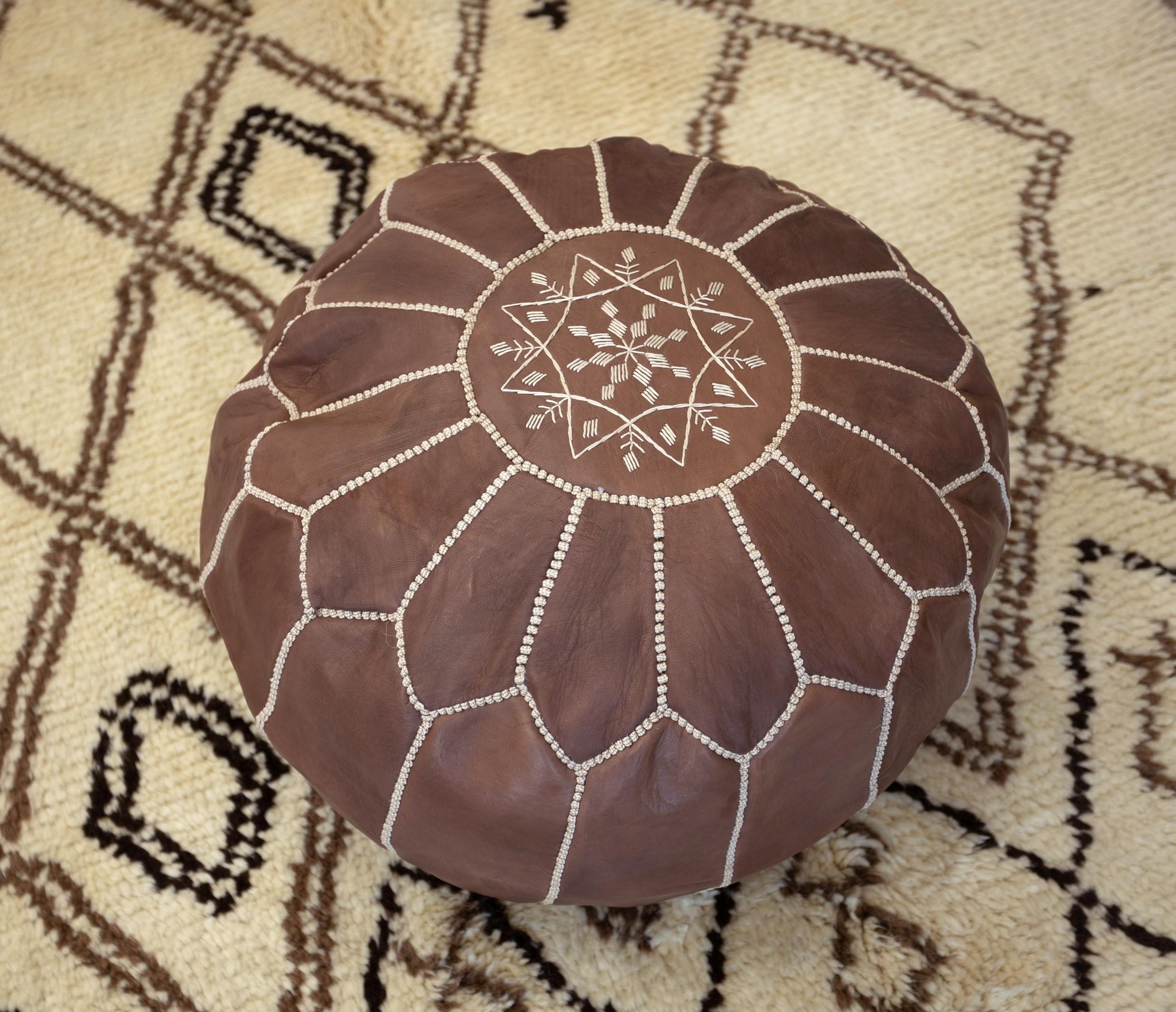 Apportez une touche de charme marocain à votre intérieur avec ce pouf exquis en cuir marron travaillé à la main. Fabriqué par des artisans qualifiés à partir de 100 % de cuir véritable, ce pouf met en valeur le savoir-faire traditionnel marocain,