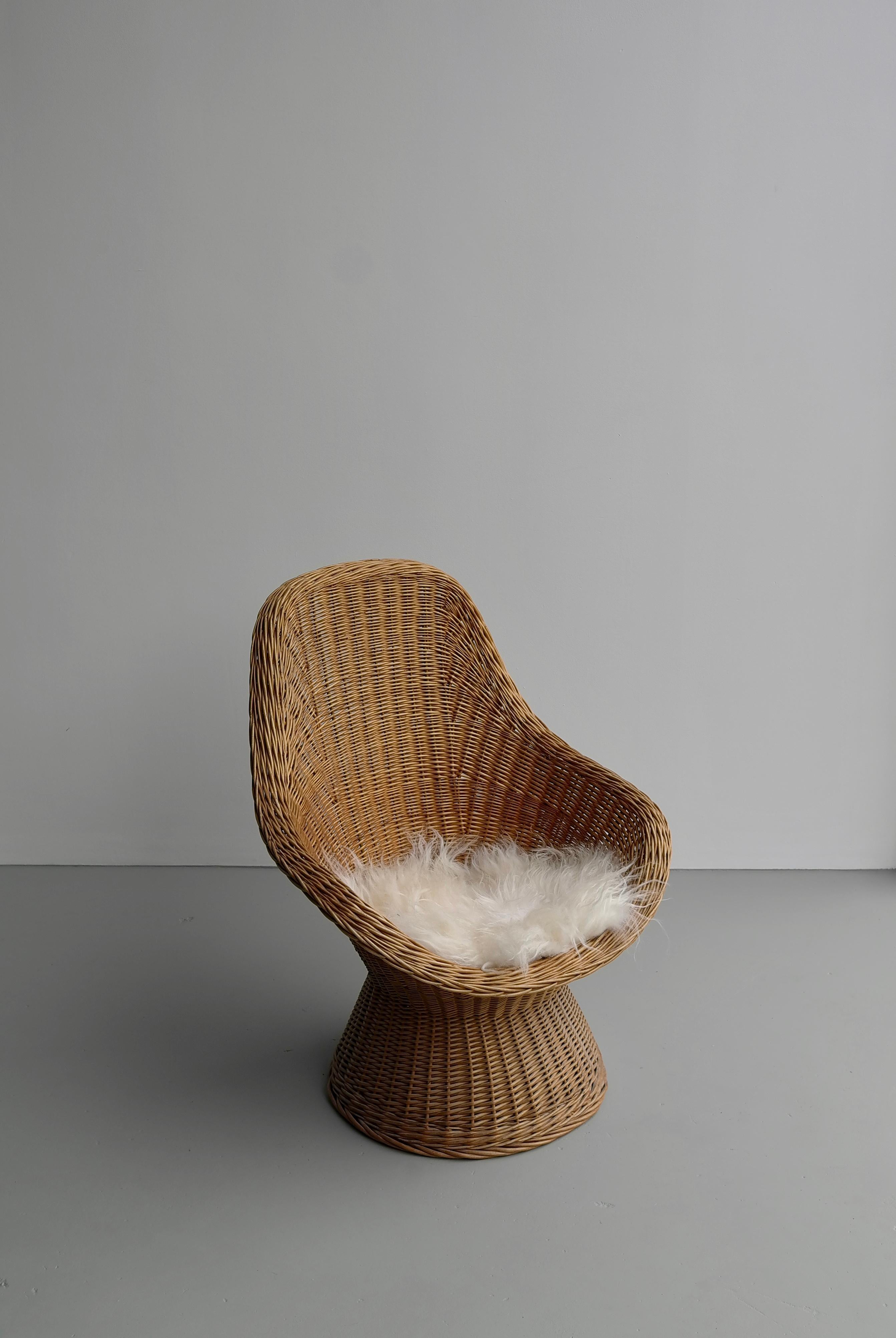 Hand twined blond willow lounge chair with white sheep wool pillow.