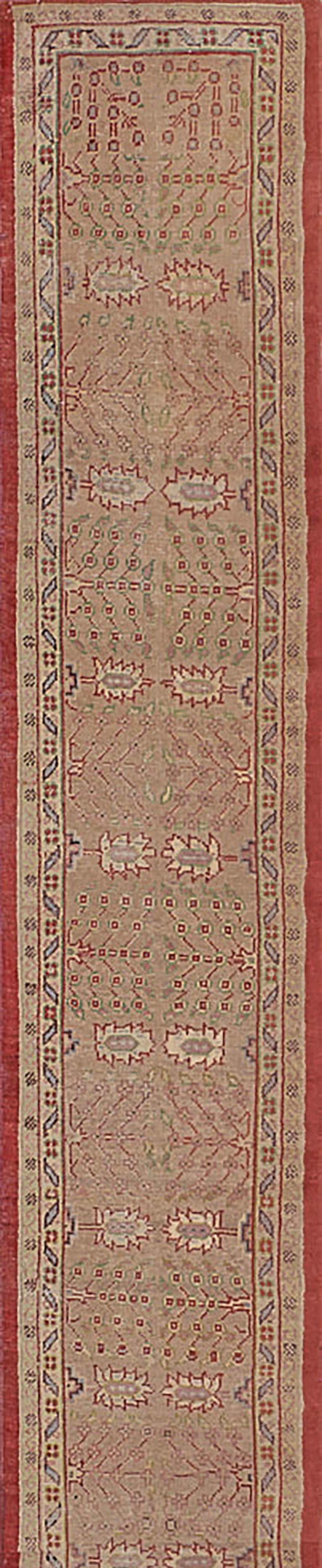 This antique, circa 1900, Oushak rug has a soft terracotta-pink field with bold paired sandy-yellow trees at each side alternating with paired vases issuing angular floral sprays, in a narrow sandy-yellow border of shaded green and tomato-red
