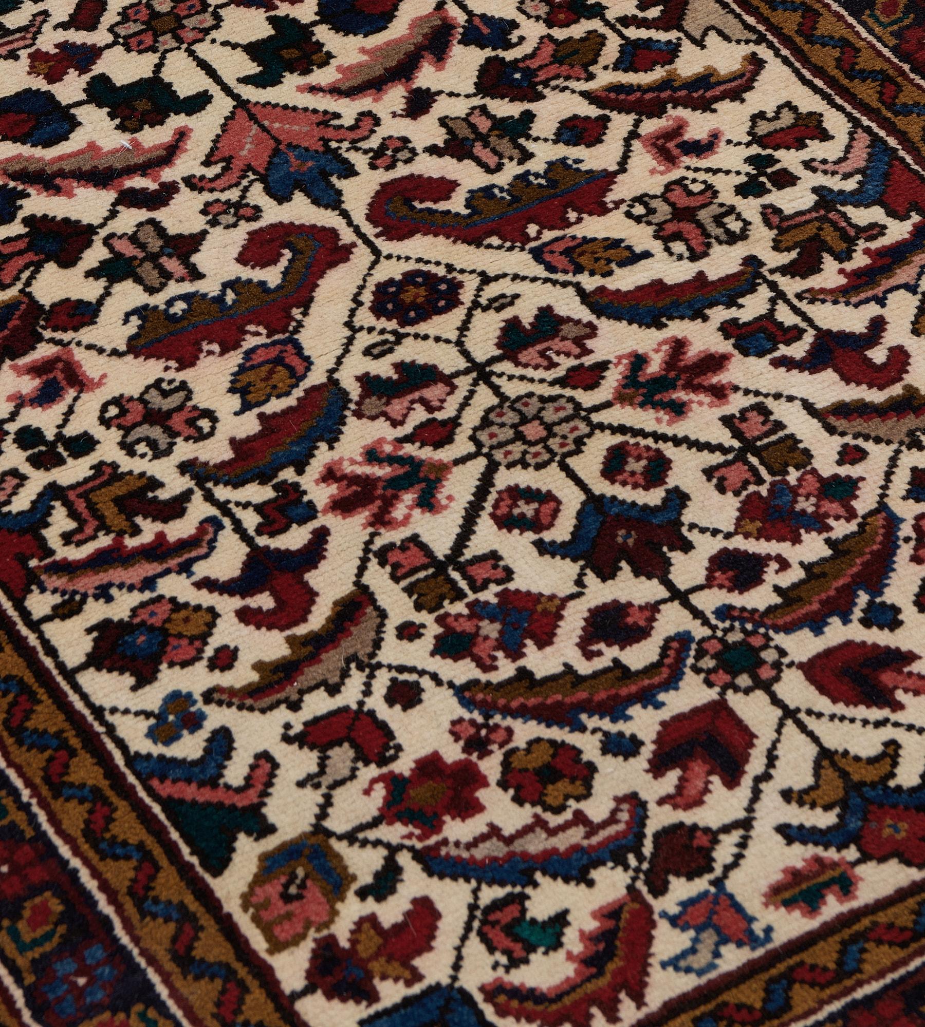 This antique, circa 1920, Heriz runner has an ivory field with an overall polychrome palmette and serrated leaf vine, in a charcoal-blue border of angular palmette and floral vine between camel-brown ribbon pattern stripes, plain outer fox-brown and