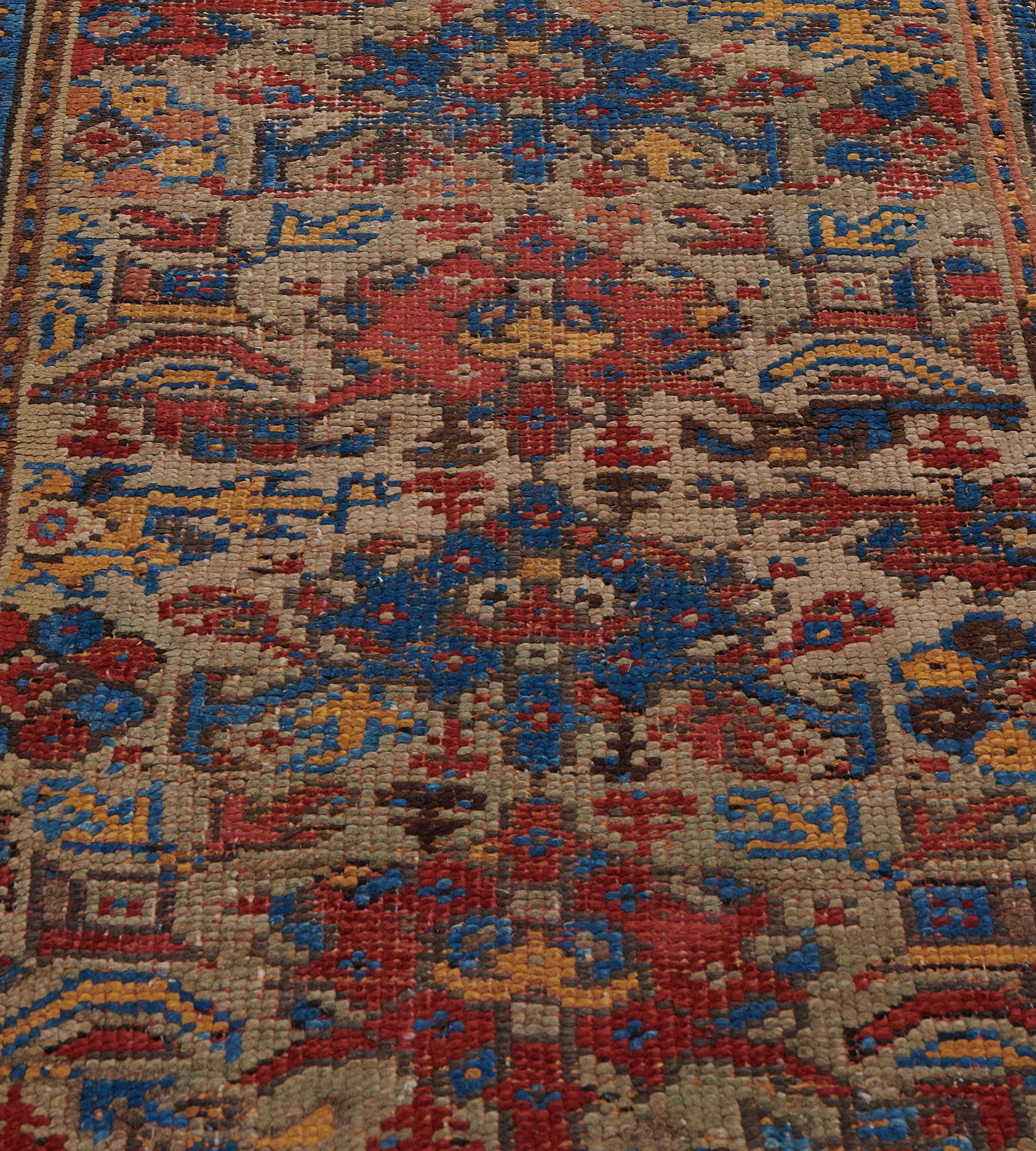 Questo antico runner Oushak, risalente al 1890 circa, presenta un campo verde con una colonna centrale di losanghe rosso mattone e blu sfumato, ciascuna circondata e collegata da fiori angolari e foglie di vite e altre rosette policrome, in uno