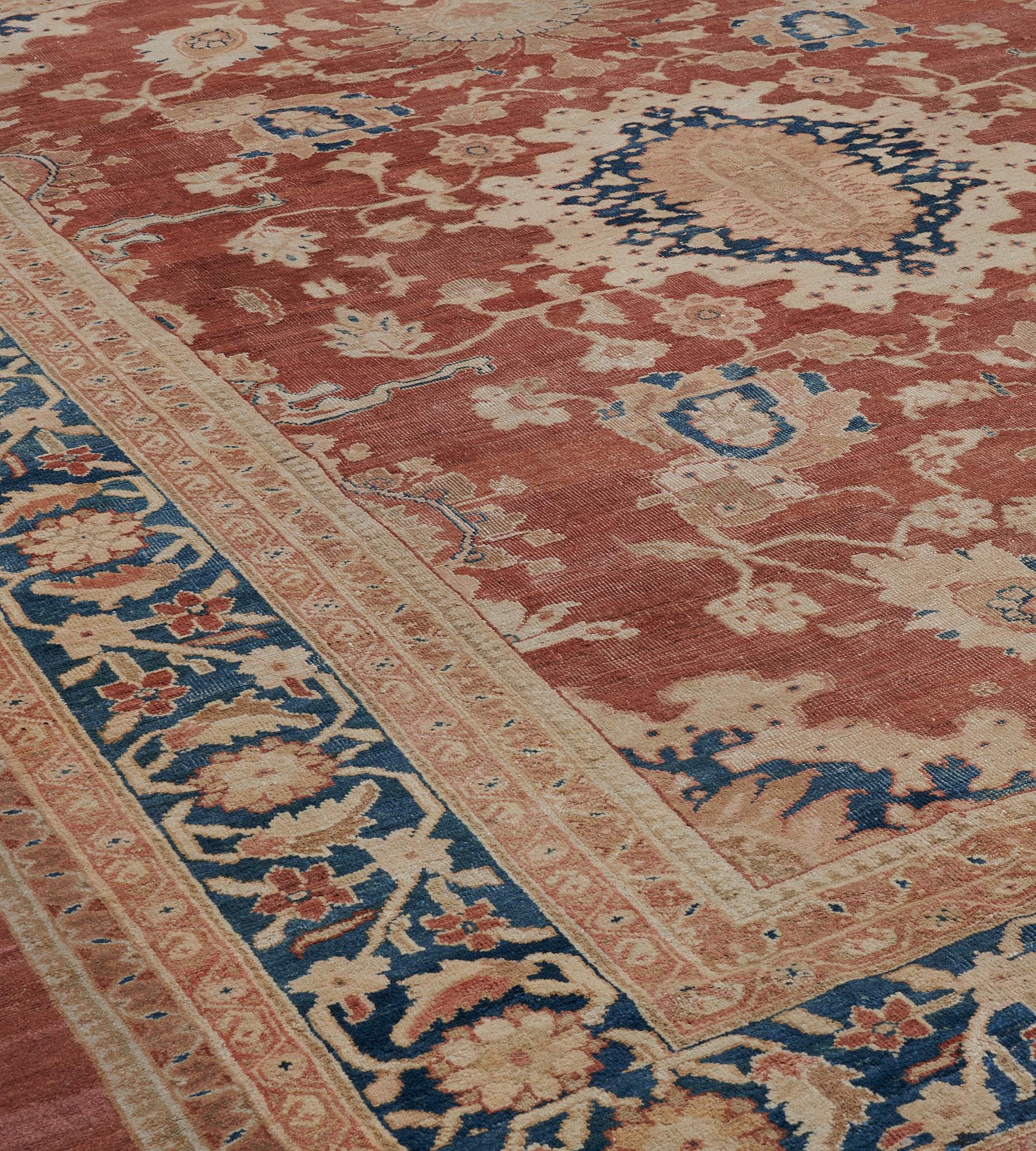 This antique Sultanabad rug has a rust-red field with a central ivory medallion with an indigo-blue and buff-brown floral lozenge surrounded by scrolling floral and palmette vine with a bold buff-brown palmette at each end issuing flowerhead and