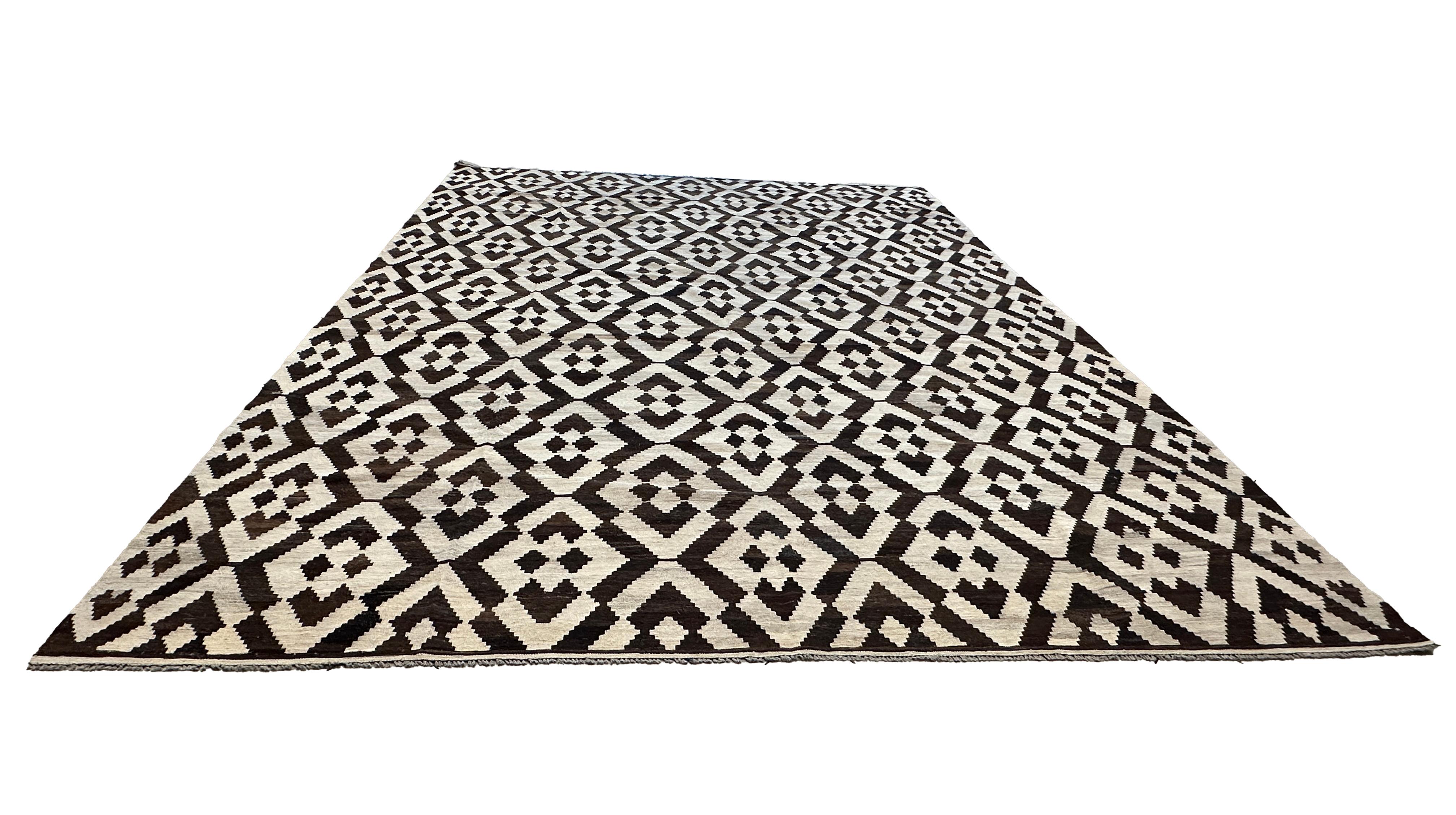 Introduce a bold and stylish statement to your home with this Hand-Woven Brown and Cream Zig-Zag Diamond Kilim Flat Weave Area Rug. Expertly crafted by skilled artisans, this rug features a striking zig-zag diamond pattern in rich brown and cream