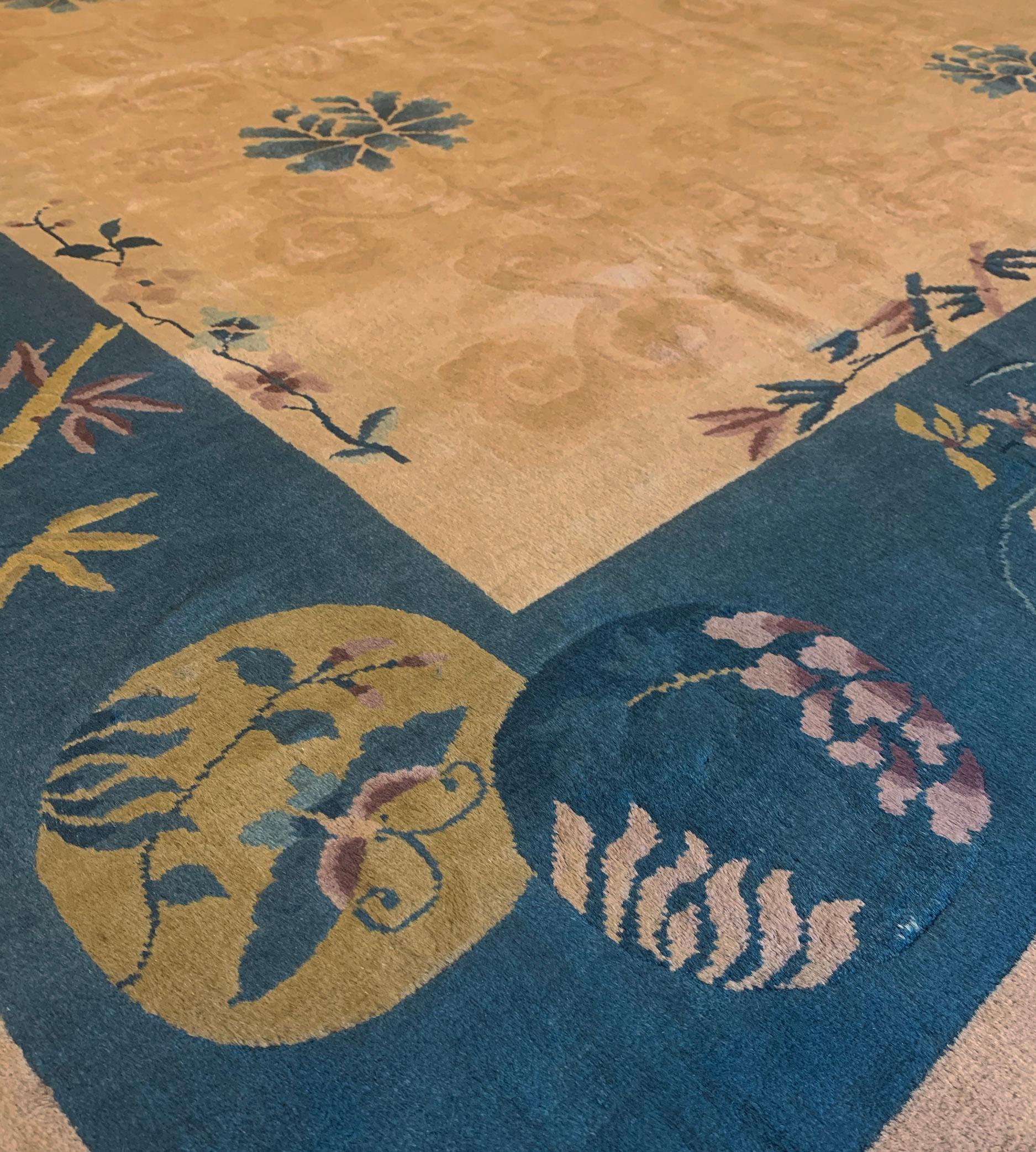 Ce tapis chinois traditionnel tissé à la main présente un champ beige raffiné avec des rangées diagonales de fleurs de lotus stylisées émettant des lianes sinueuses sourdes, dans une bordure bleu nuit ou des bouquets clairsemés, des vases fleuris et