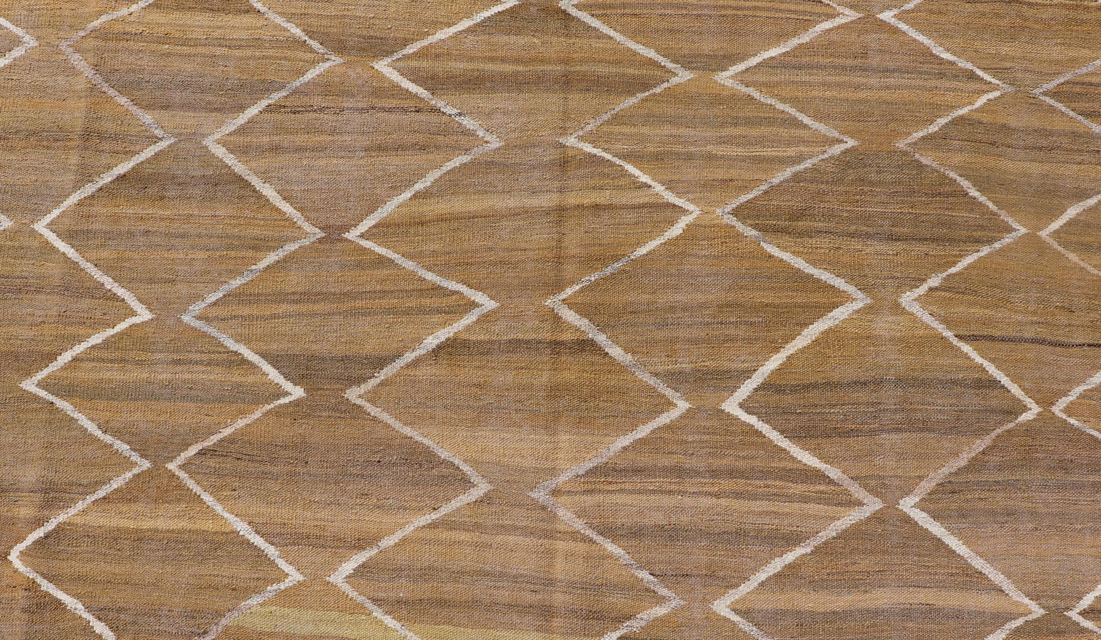 Questo kilim a trama piatta è stato tessuto a mano. Il tappeto presenta un moderno disegno a diamante, realizzato nei toni dell'oro, dell'avorio e del marrone; questo tappeto si adatta perfettamente a una varietà di interni classici, moderni, casual