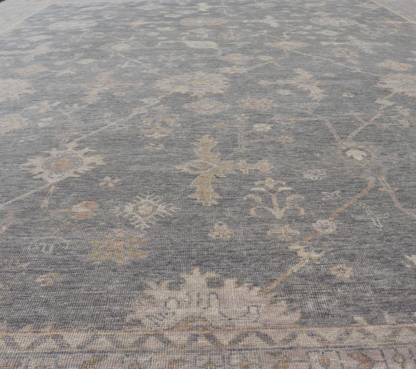 Tapis indien en laine Oushak tissé à la main avec des bleus et des gris délavés. 
 Mesures 11'10 x 15'2 
Pays d'origine : Inde ;  Type : Oushak ;  Design/One : All-Over, Floral ; Keivan Woven Arts ; tapis IN-TVN-1411 ; Grand tapis indien en laine