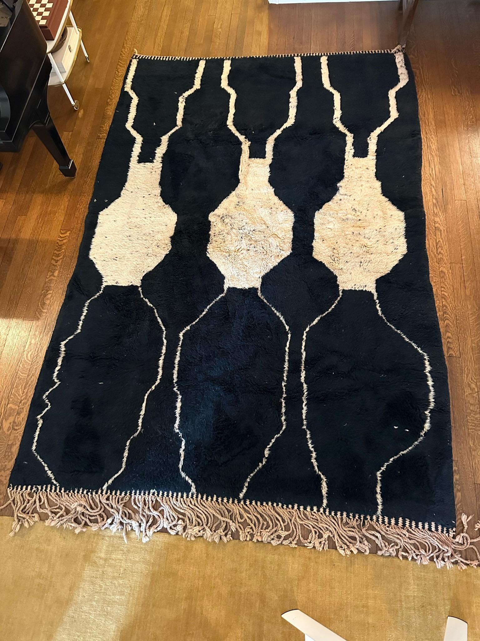 Handwoven Moroccan rug purchased from a local artisan in Morocco. The eclectic pattern and contrasting colors add a unique touch to this beautiful piece. The rug has two binded edges and two frayed edges.