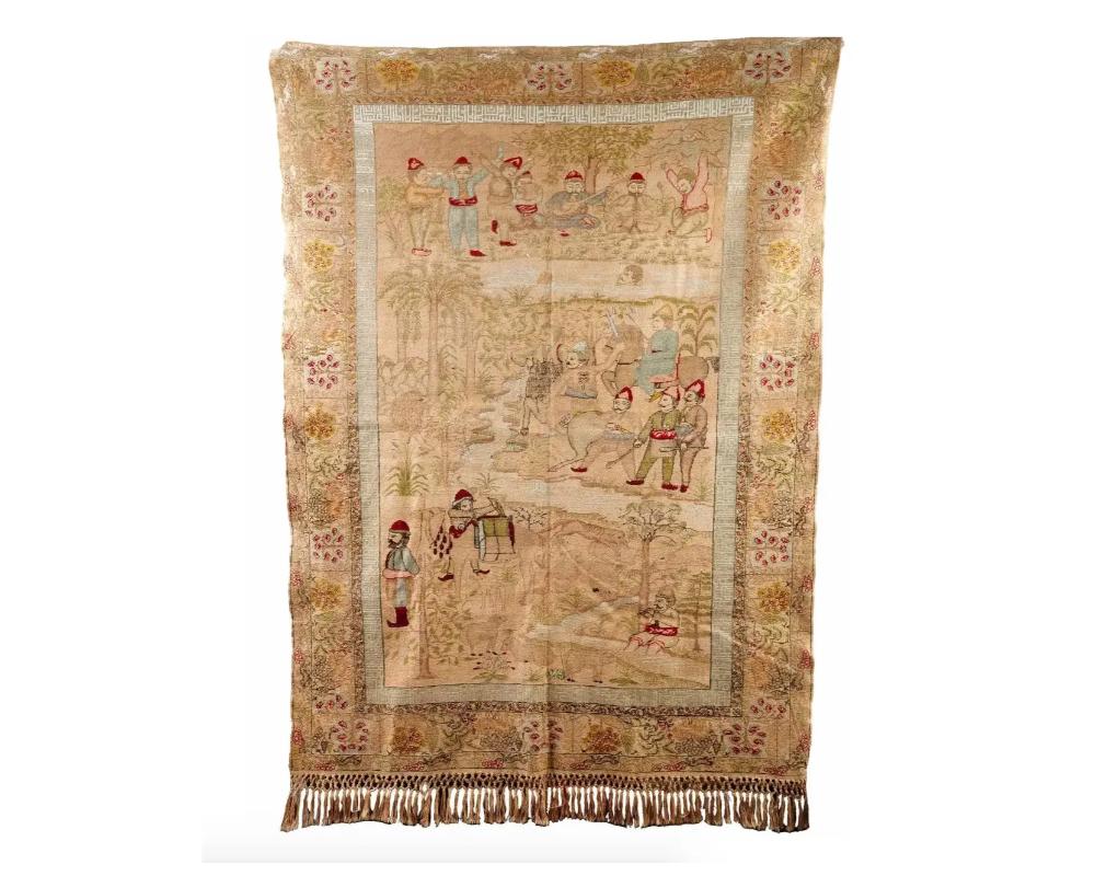 A pictorial Turkish hand-woven pure silk carpet depicting highly detailed scenes with human figures in a landscape on a beautiful gold tone silk ground. The upper scene depicts men playing music, the middle scene depicts a group of men hunting a