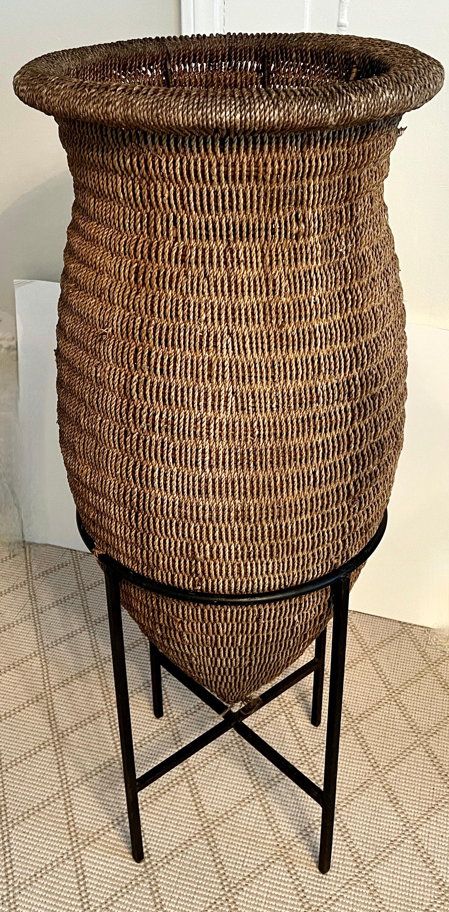 Cesta asiática de ratán tejida a mano sobre soporte de hierro forjado Tribal en venta