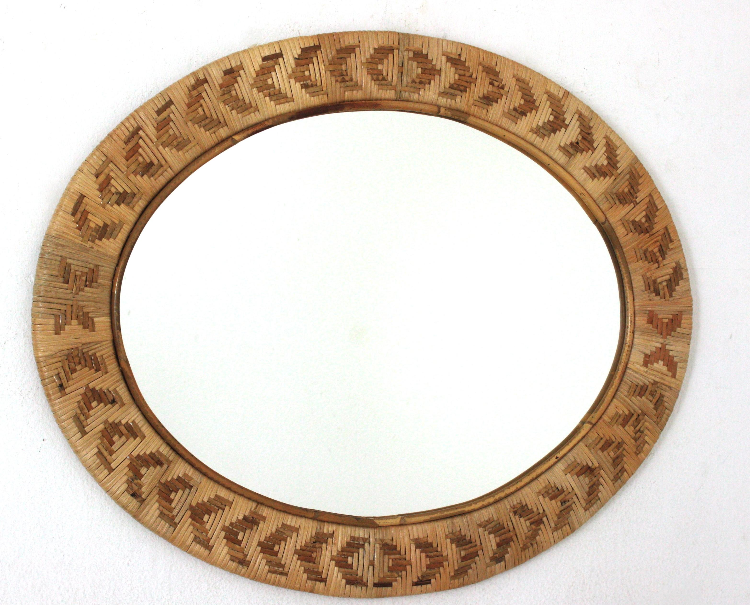 Hand braided wicker rattan oval mirror. Spain, 1960s.
Rare find.
On a wooden structure this oval mirror was upholstered with an artisan hand-woven wicker work.
Hundreds of wicker or rattan straps are nicely braided creating geometric