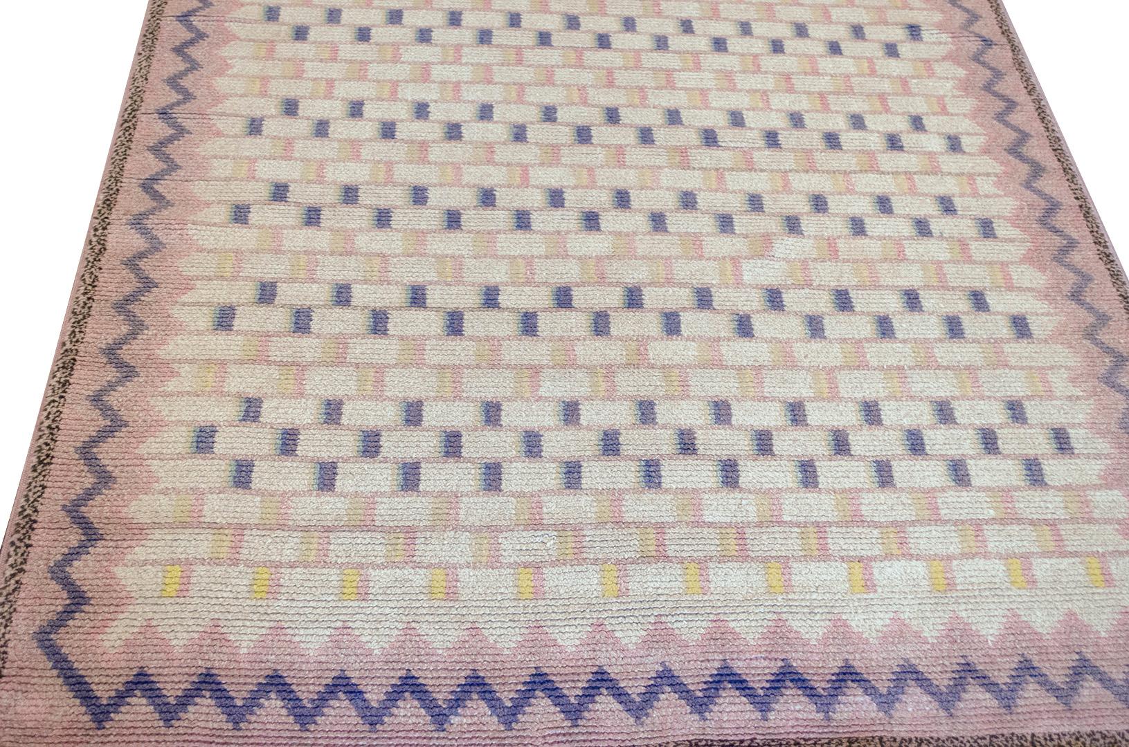 This traditional handwoven Swedish Deco rug has an overall field of checkered purple, pink, and pale yellow rectangles in a zig-zag pink border, with zig-zag narrow purple stripe and outer stripe consisting of black and taupe pixels.