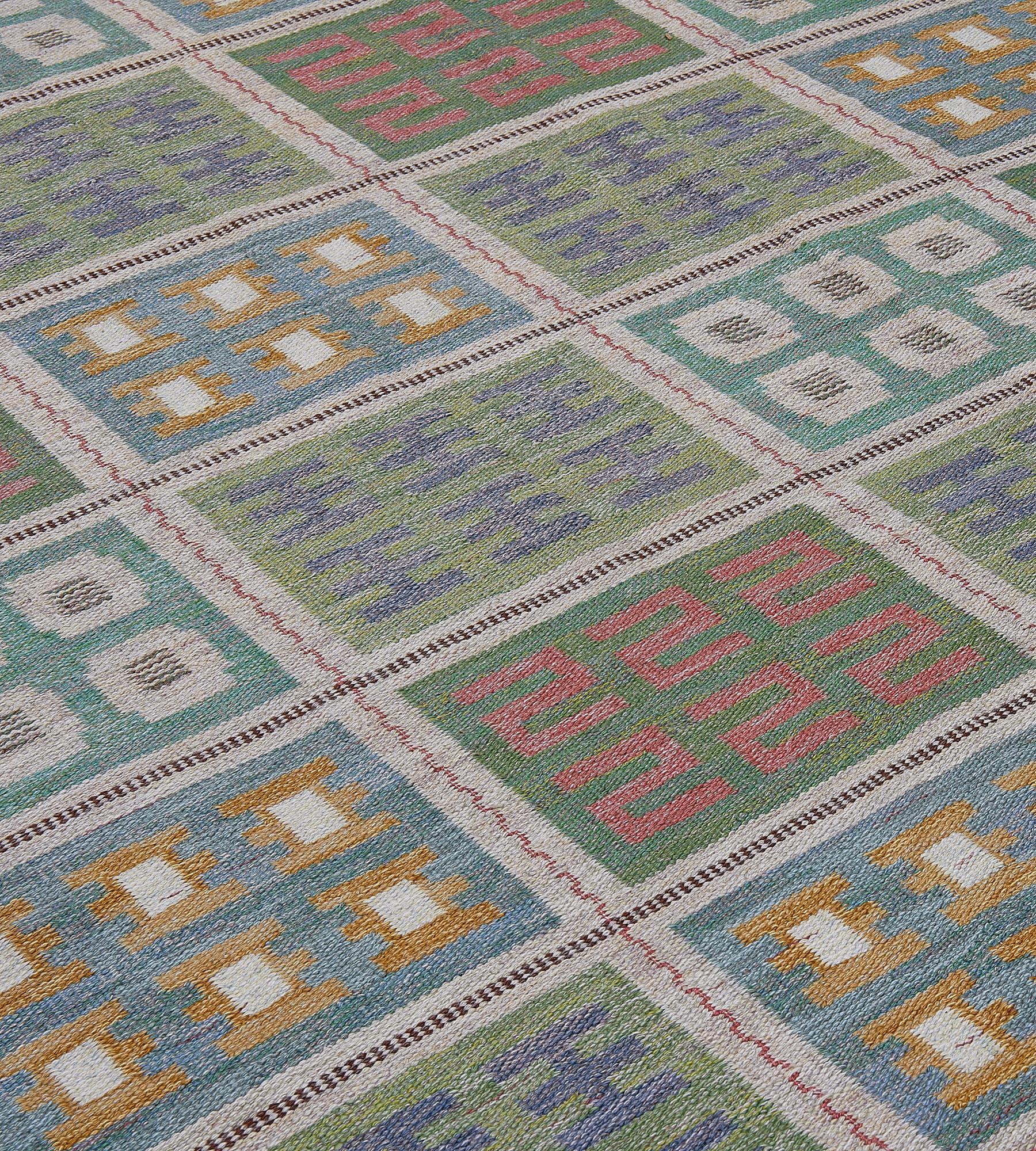 This vintage Swedish flatweave rug has a field with five vertical columns of eight rectangular boxes each containing a sea-green, light blue and moss-green smaller box with a variety of six polychrome different decorative motifs, all linked by an