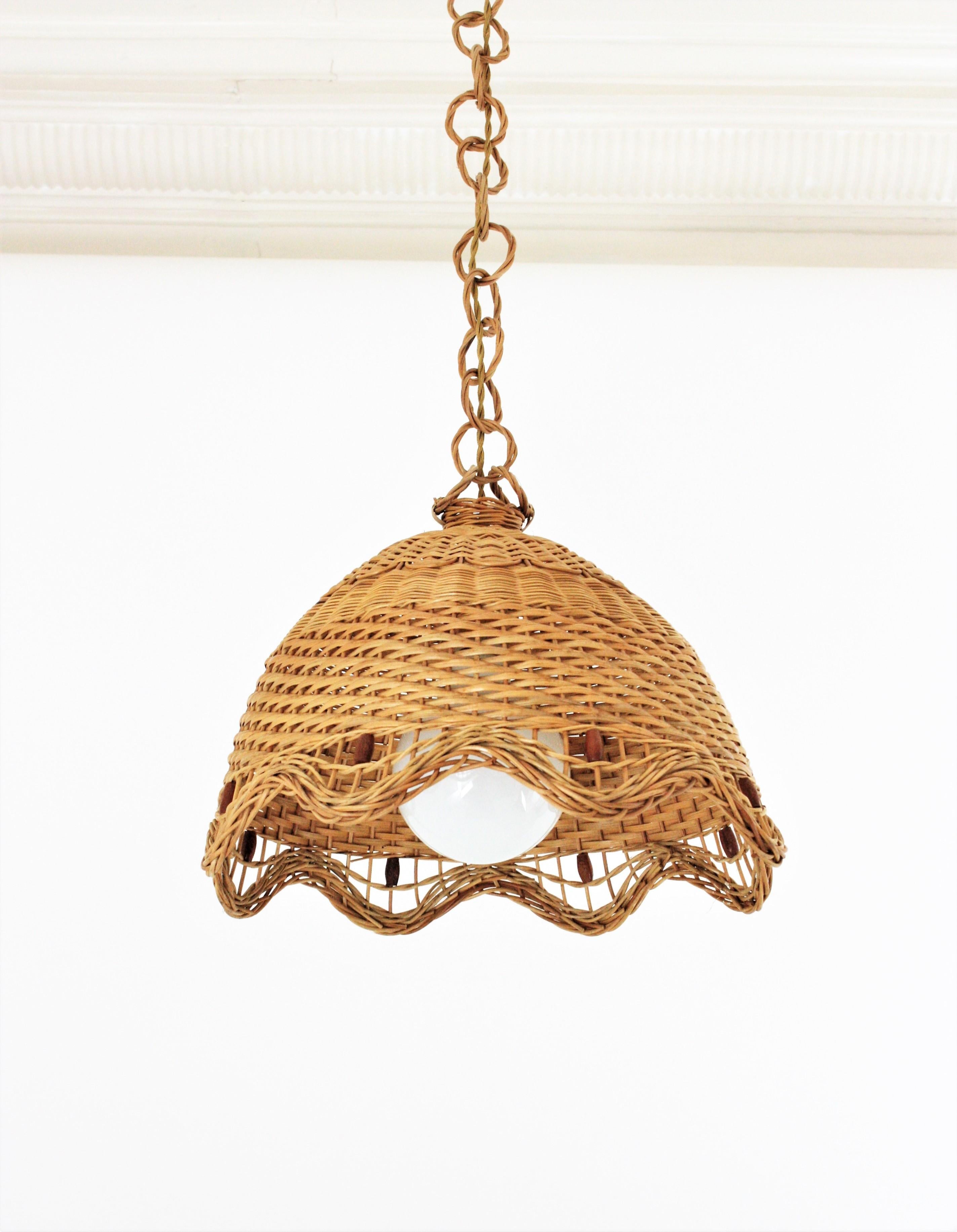 Eye-catching Lantern Woven Light Pendant in natural wicker and rattan with Scalloped Edge. Spain, 1960s.
This hand-crafted bell shaped hanging lamp features a woven wicker shade accented with brown cylinders as decorative details. It hangs from a